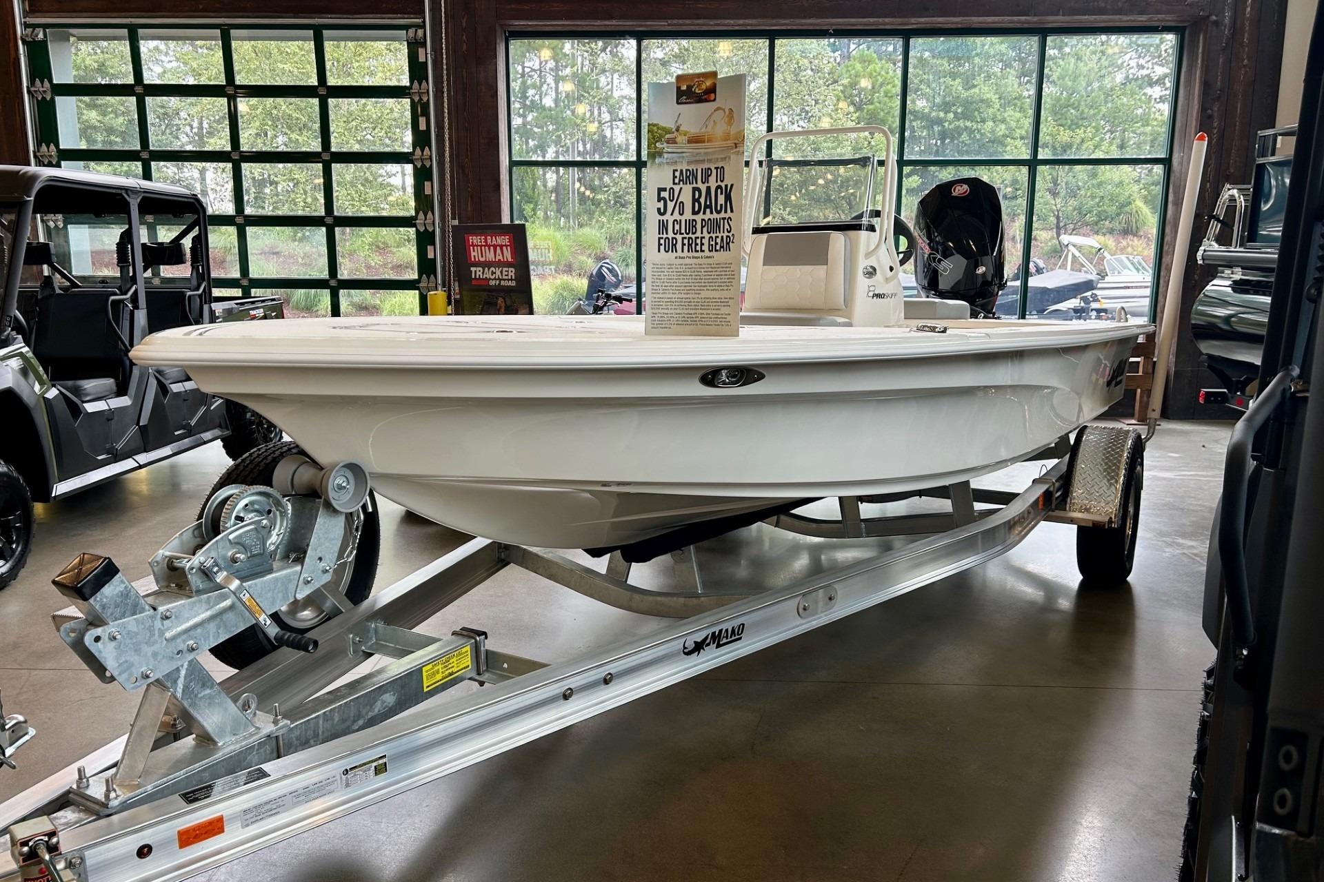 2026 Mako Pro Skiff 18 boat on trailer in showroom, promotional sign displayed.
