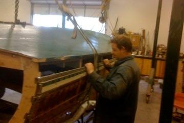 Person working on 1931 Hacker-Craft 26 Dolphin boat restoration in workshop.