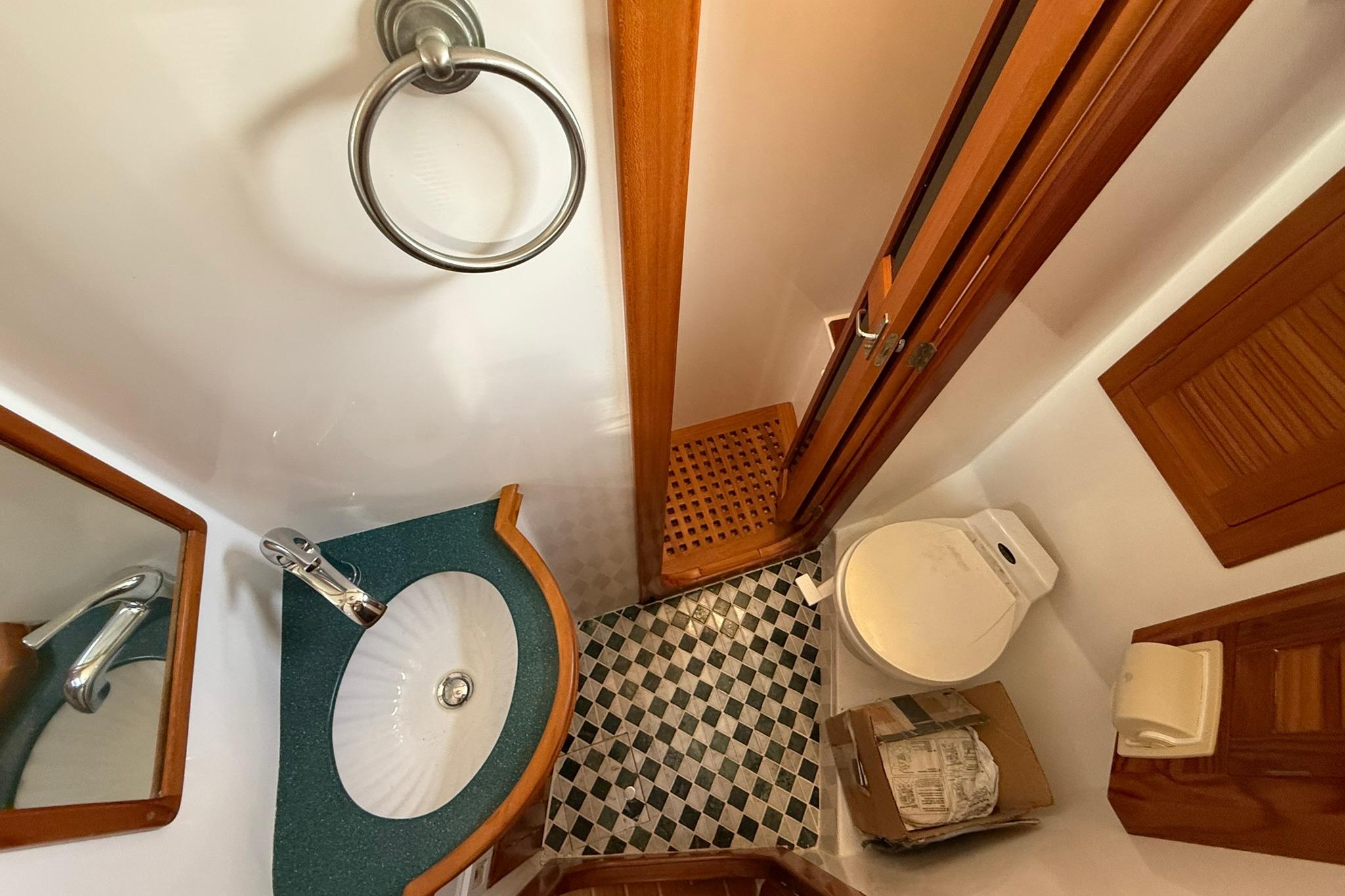 Compact bathroom in 2000 Cabo Rico Cutter 45 yacht with sink, toilet, and checkered floor.