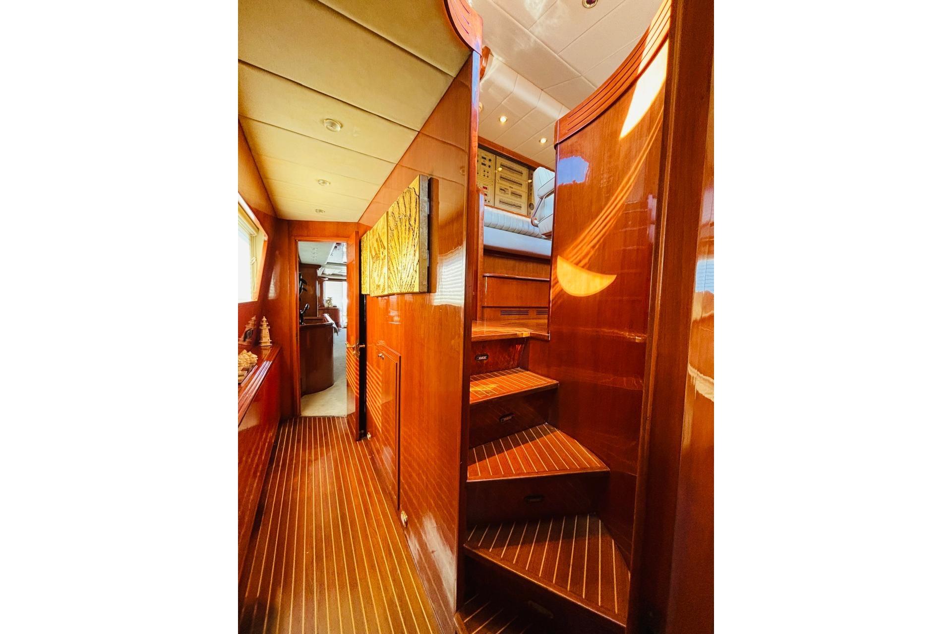 Luxurious wooden interior of a 2000 Falcon 100 yacht with elegant staircase.