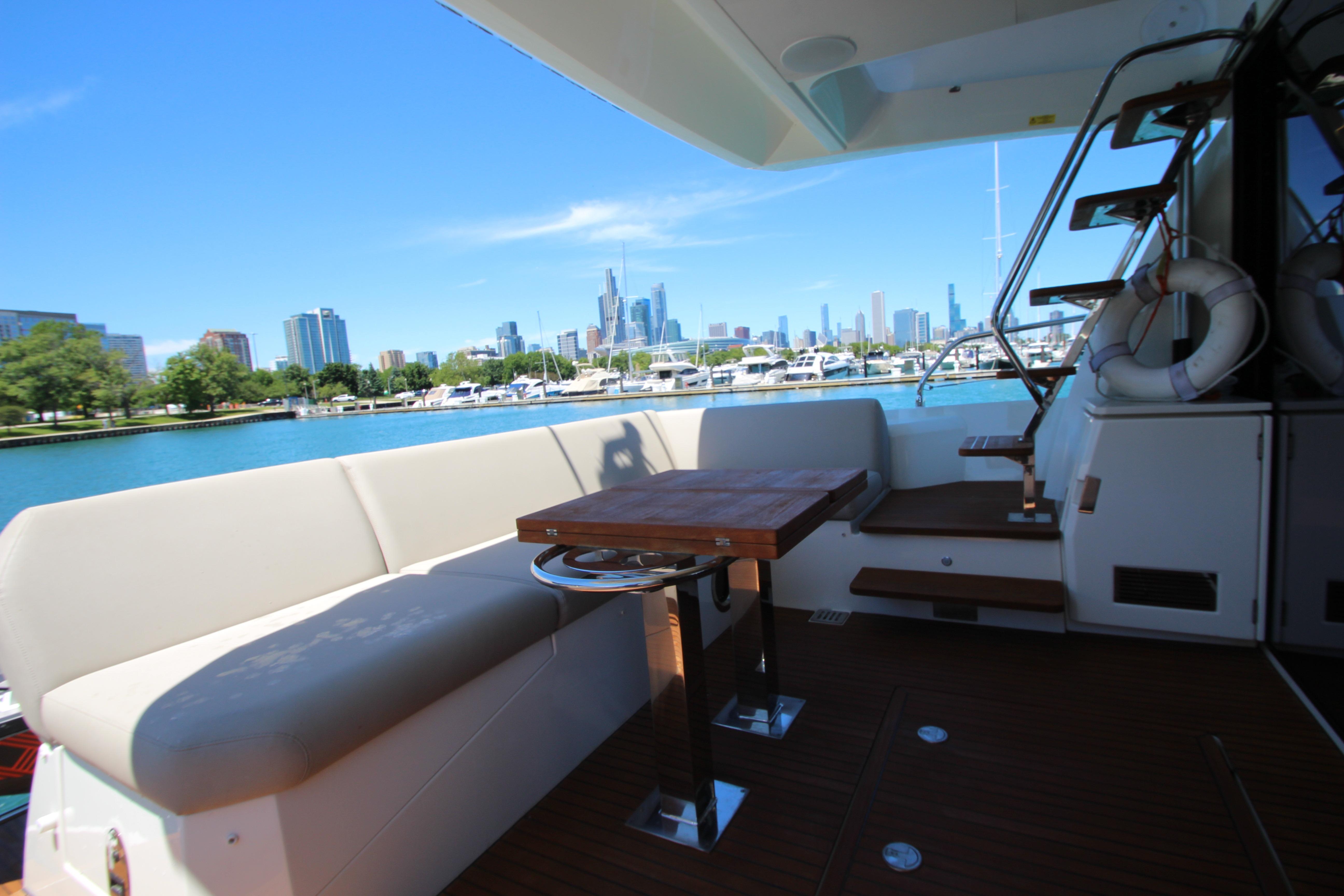 Luxurious 2022 Prestige 520 yacht deck with city skyline view, featuring seating and table.