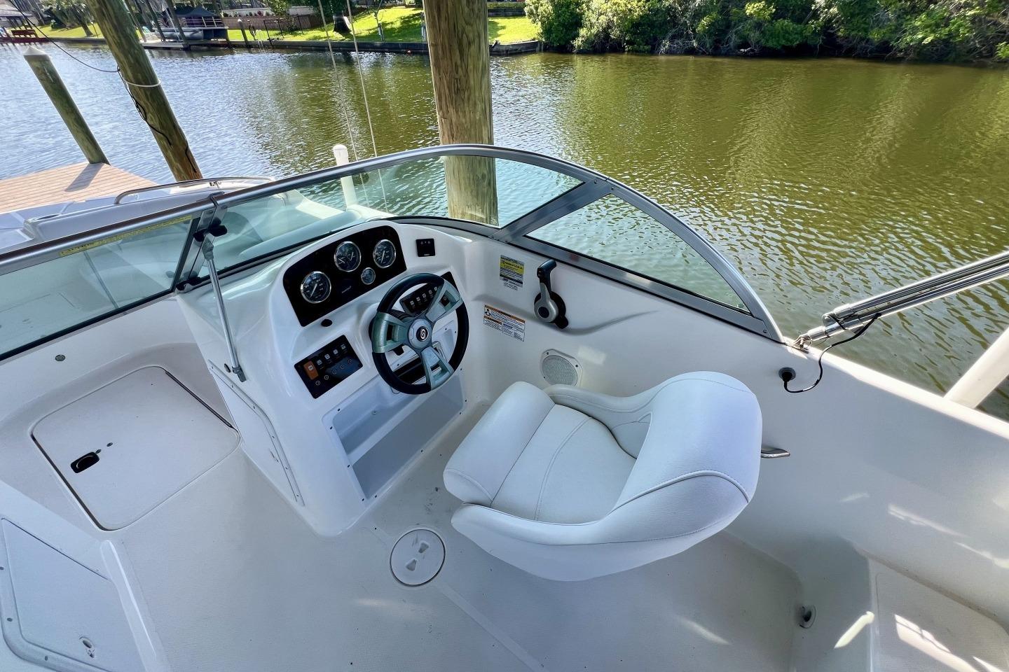 2013 Hurricane SunDeck 187 OB boat cockpit with steering wheel and white captain's chair.