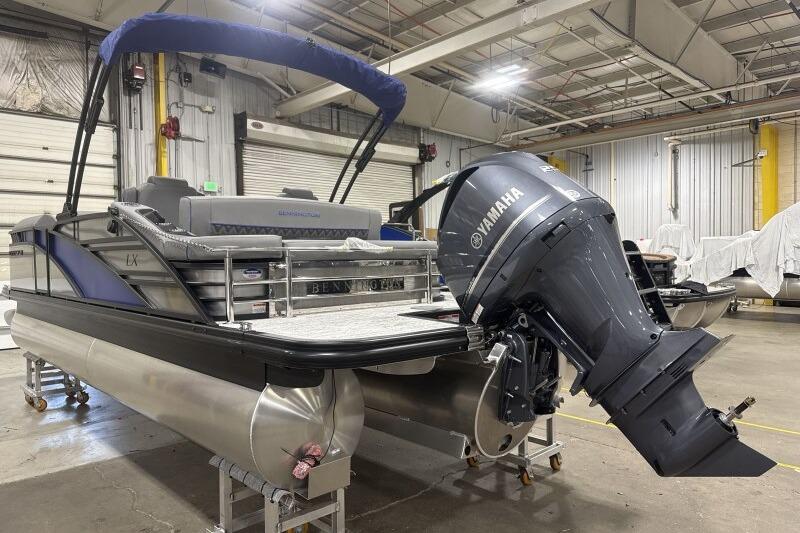 2026 Bennington 23 LXS Swingback pontoon boat with Yamaha outboard motor in a warehouse.