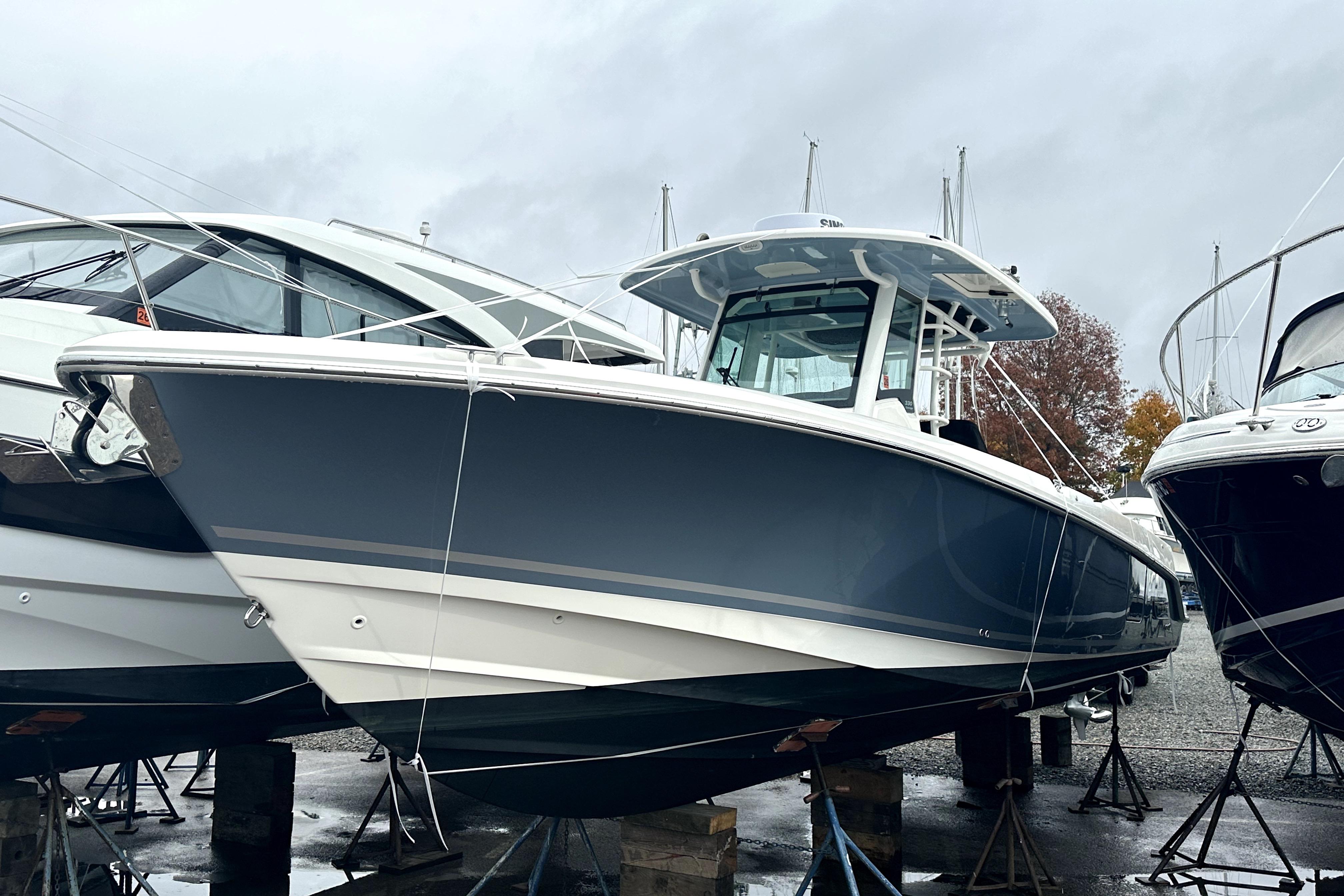 2023 Boston Whaler OUTRAGE boat on stands, displayed outdoors on a cloudy day.