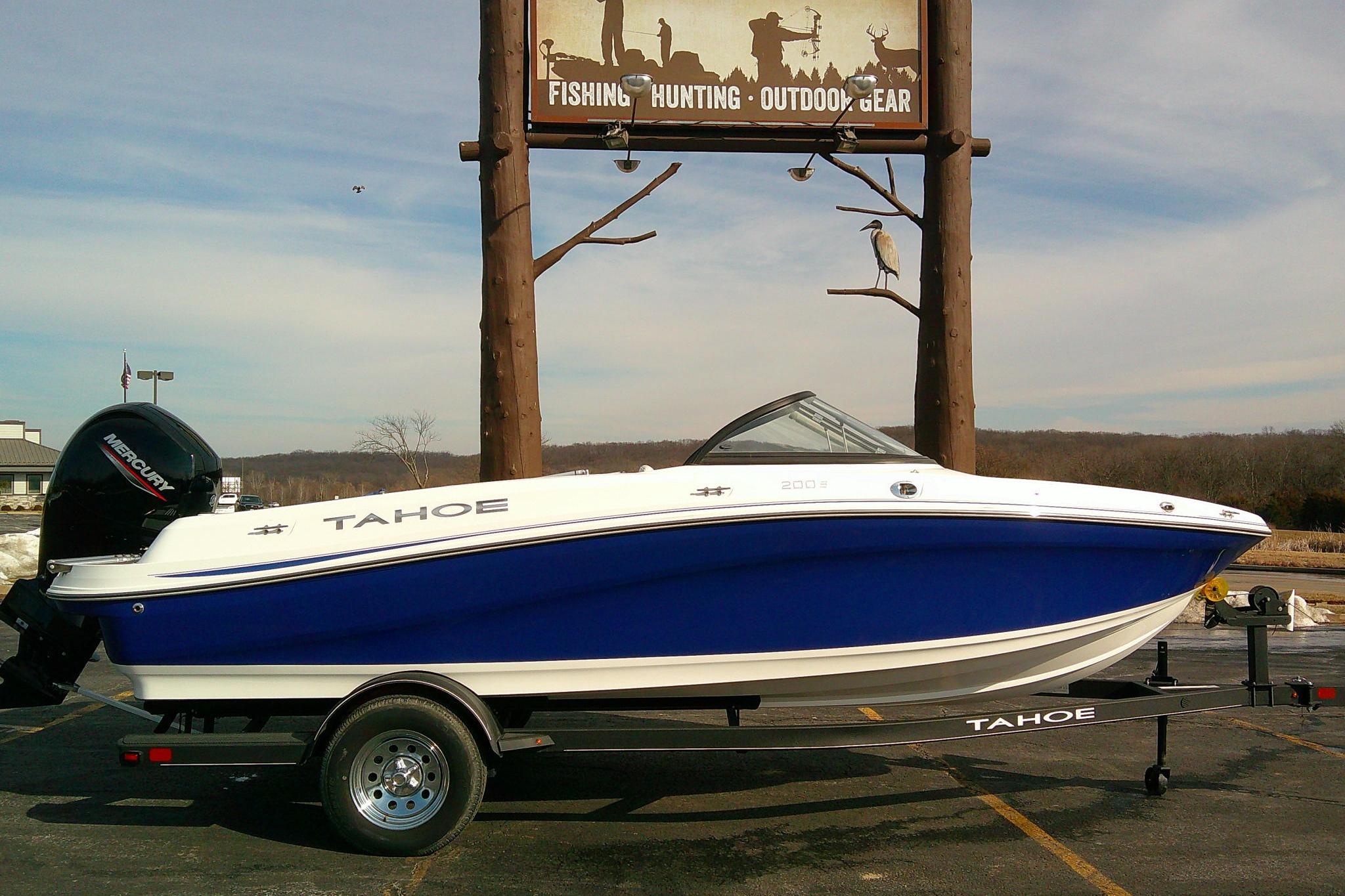 2024 Tahoe 200 S boat on trailer, parked near outdoor gear store sign.