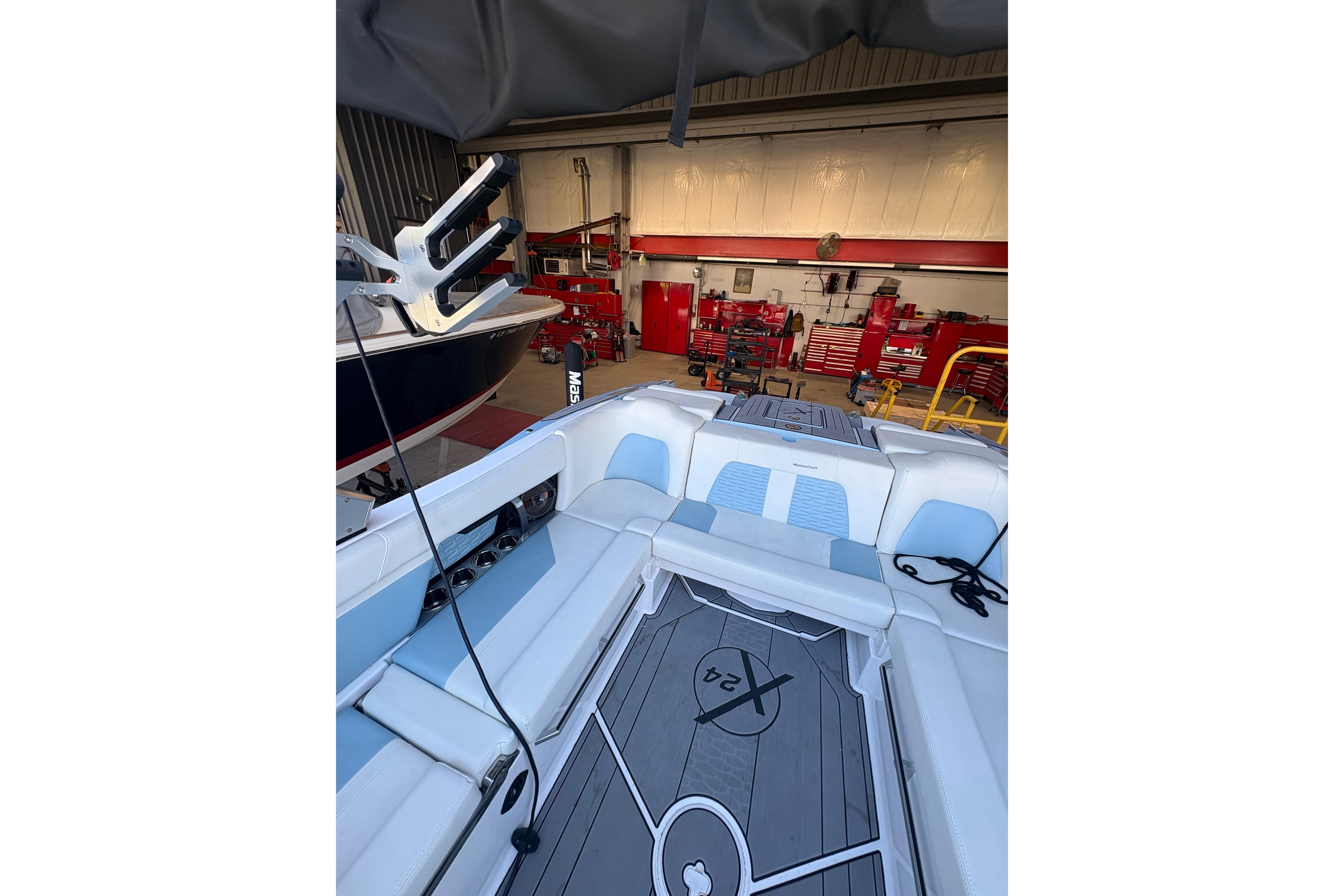 2022 MasterCraft X24 boat interior in a workshop setting, showcasing seating and deck design.