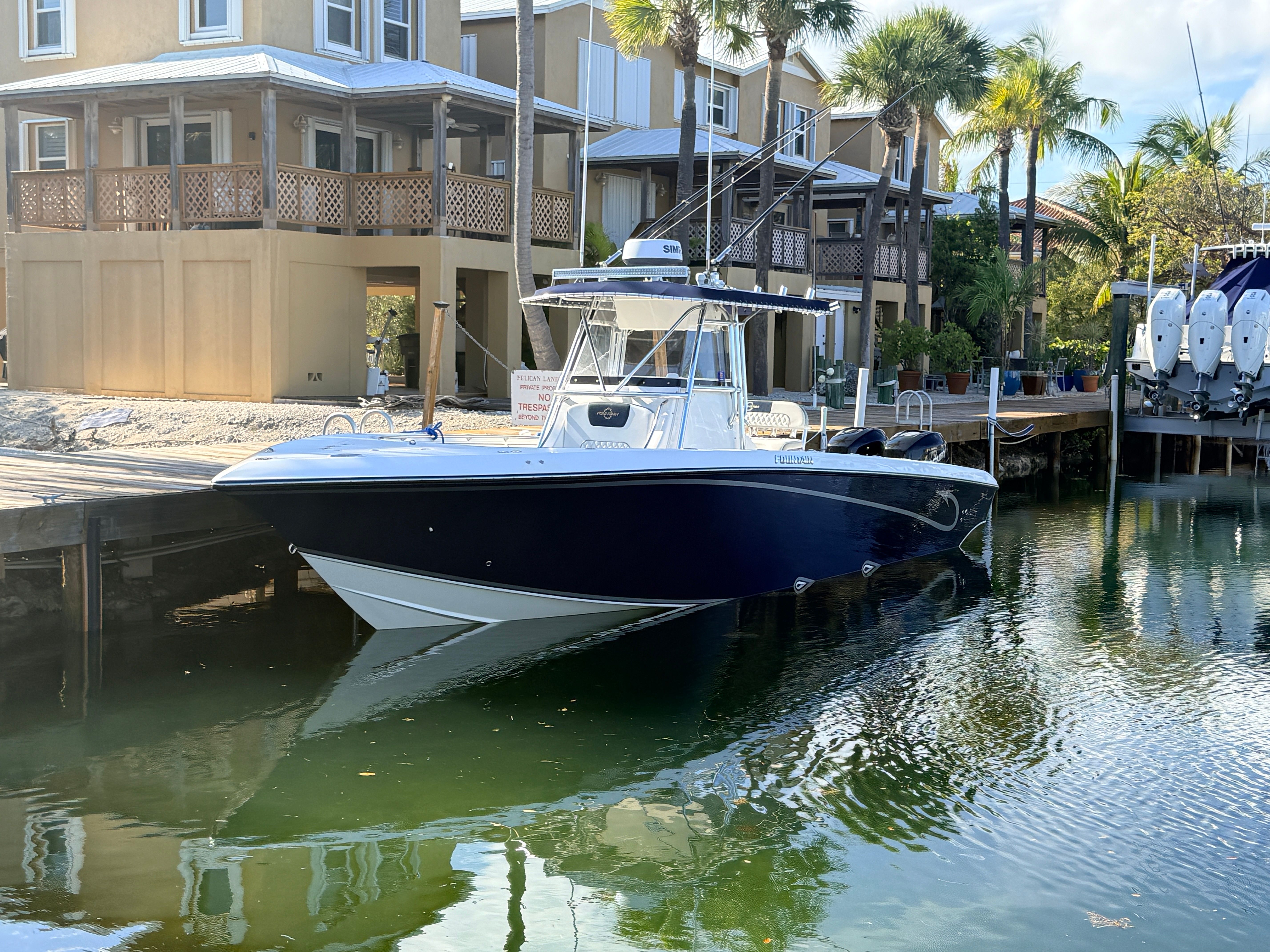 2007 Fountain 32 Center Console boat docked near palm trees.