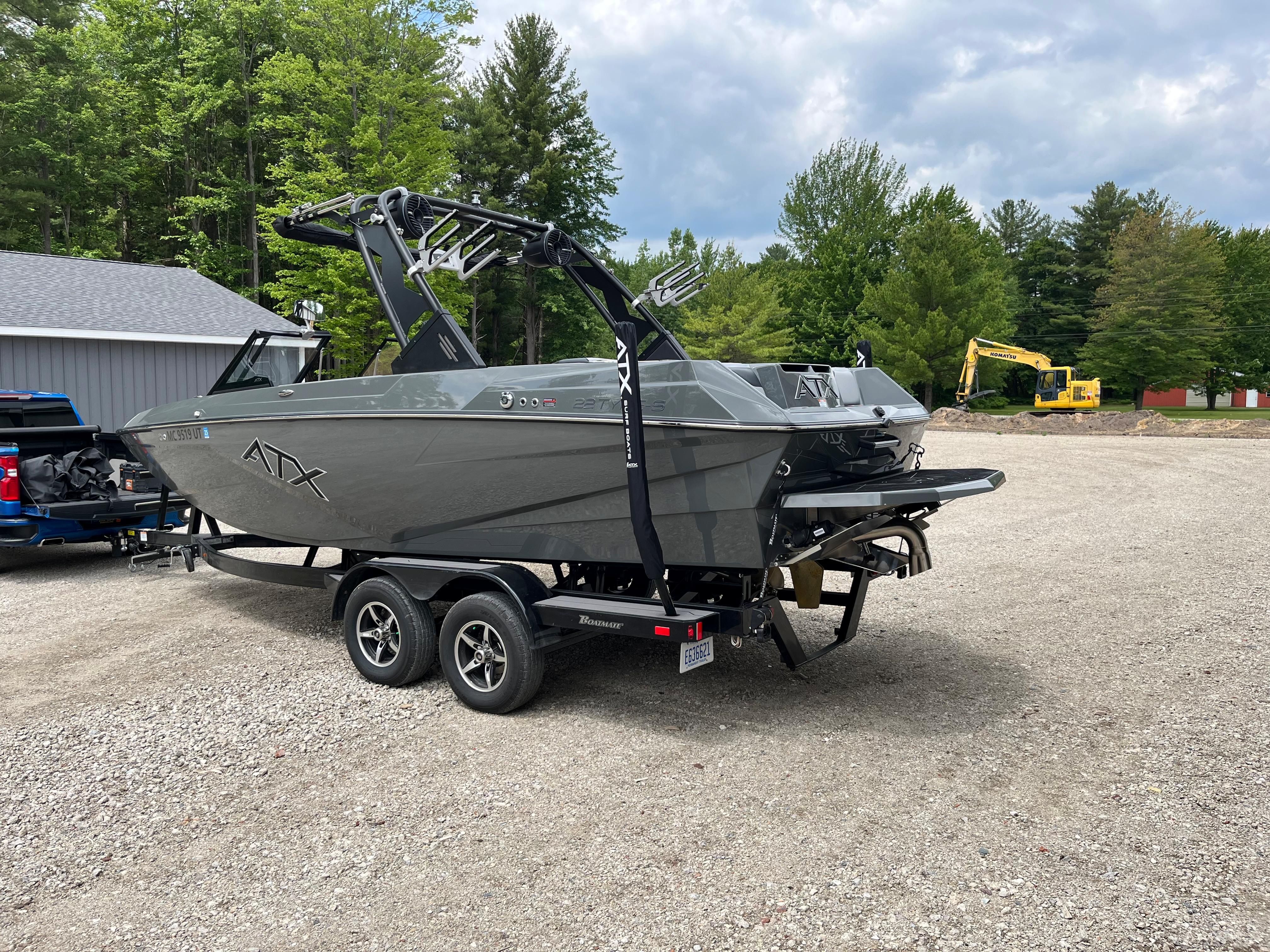 A gray 2022 ATX Surf Boat 22 Type-S on a trailer in a gravel lot.