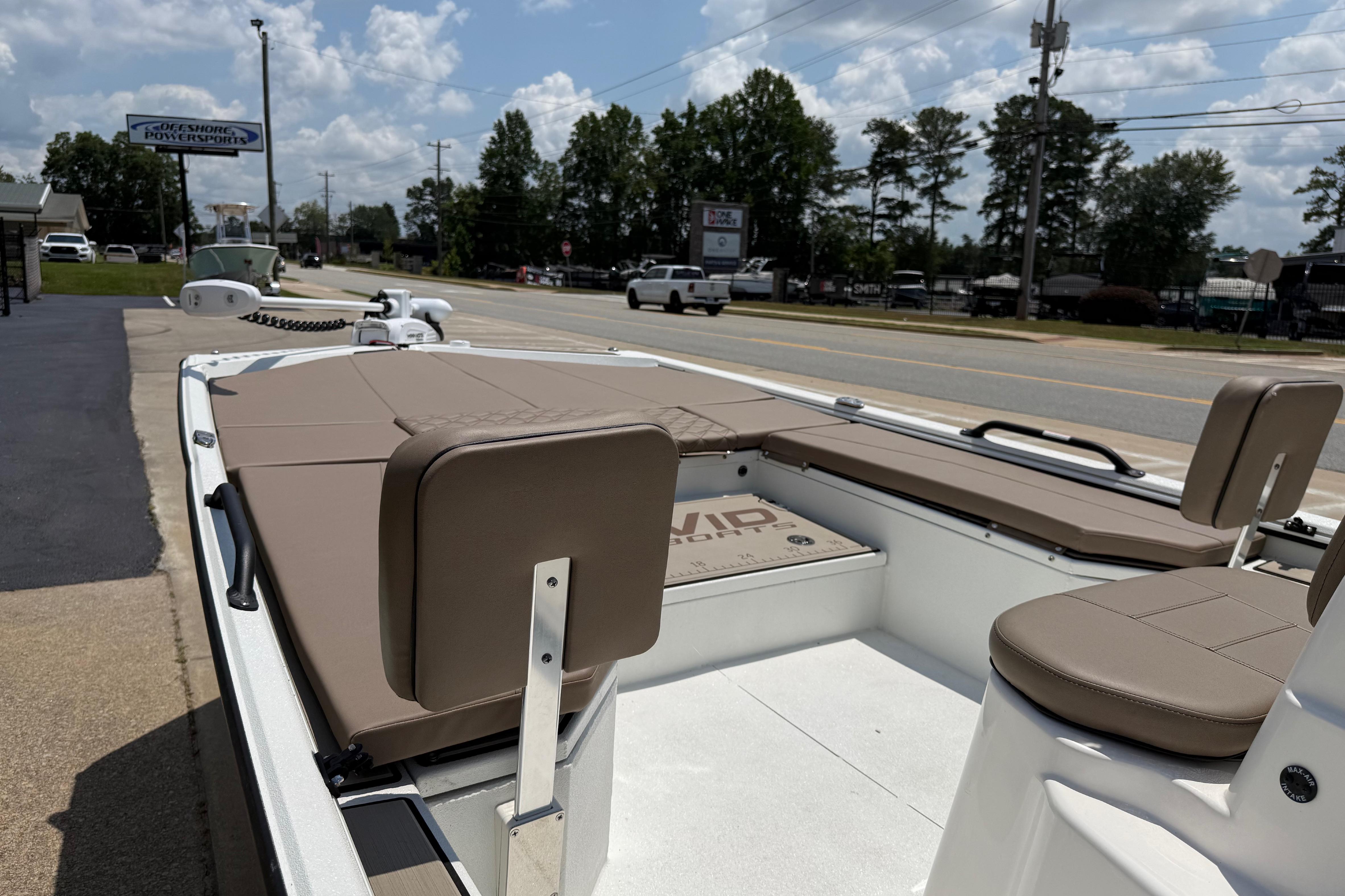 2025 Avid 22 Recon boat with tan seating, parked near a road under a cloudy sky.