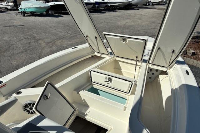 2026 Mako 24 APEX boat with open storage compartments in a marina setting.