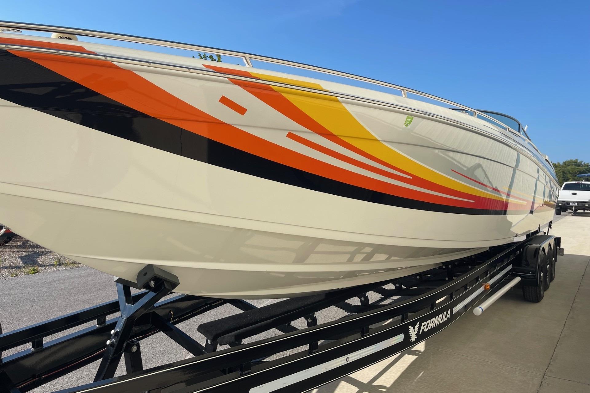 2004 Formula 382 FASTech boat with vibrant orange and yellow graphics on a trailer.