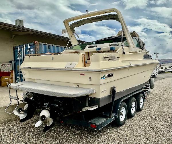 1987 Sea Ray 270 Sundancer boat on trailer, parked outdoors, with cloudy sky background.