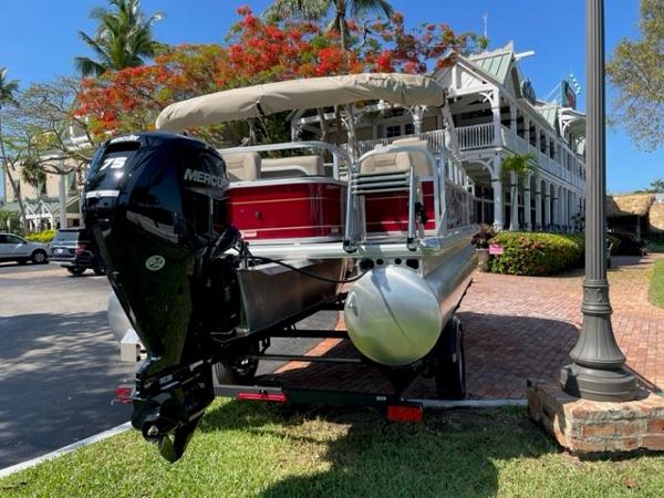 2024 Sun Tracker Bass Buggy 18 DLX pontoon boat with Mercury 75 engine, parked near a building.