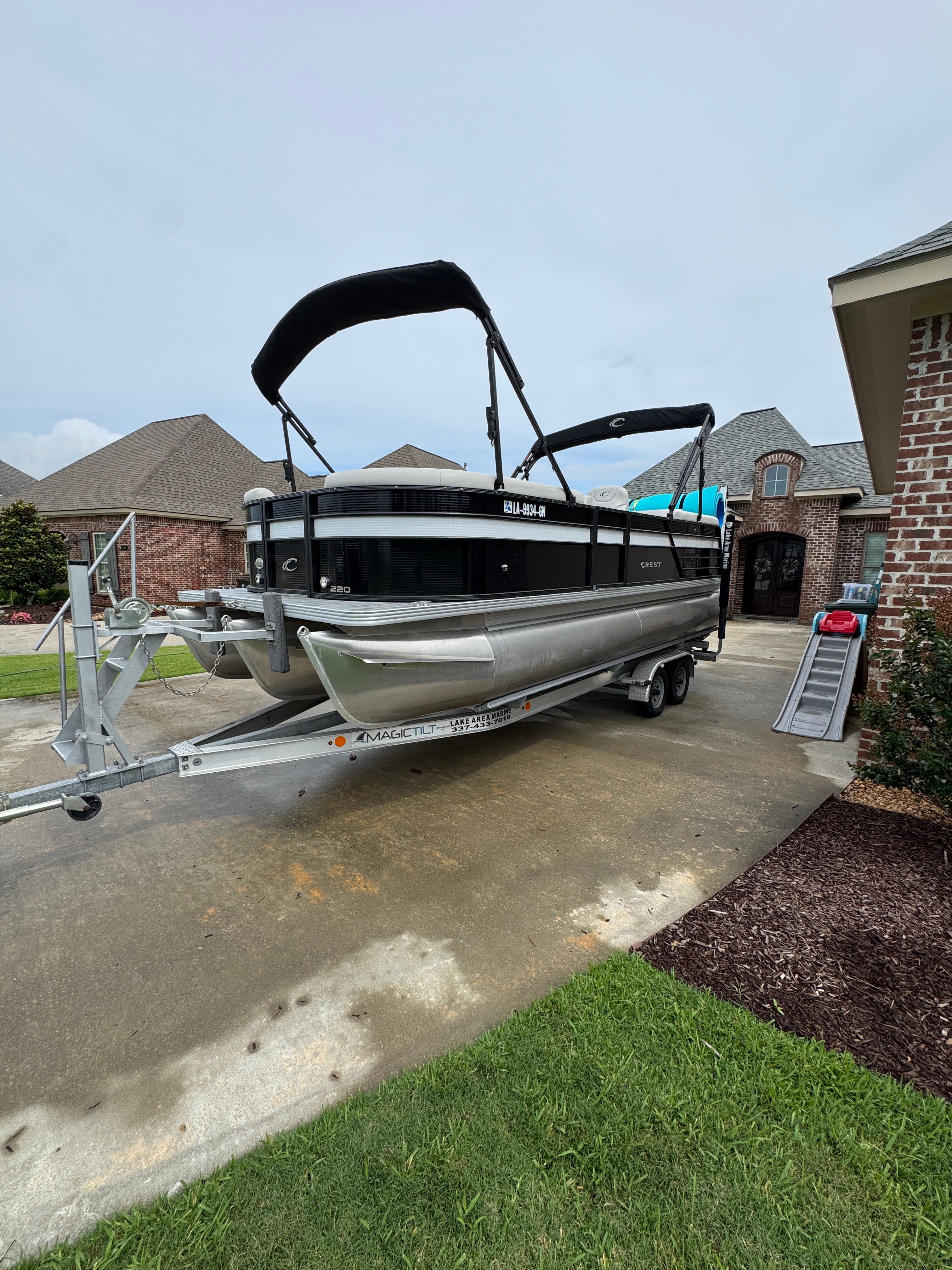 2022 Crest Classic DLX 220 pontoon boat on trailer in driveway.