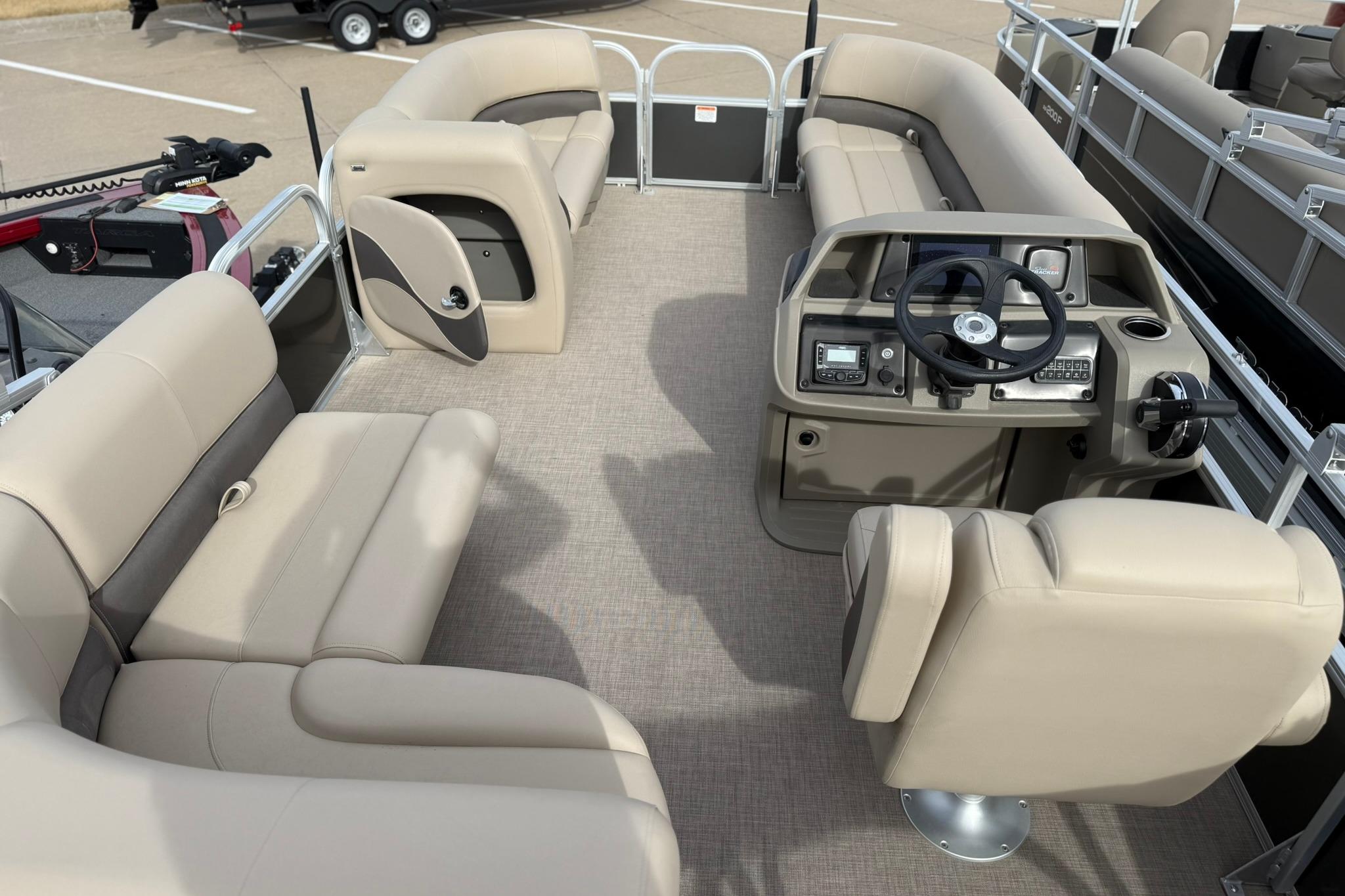 2025 Sun Tracker Party Barge 18 DLX interior with beige seating and modern helm.