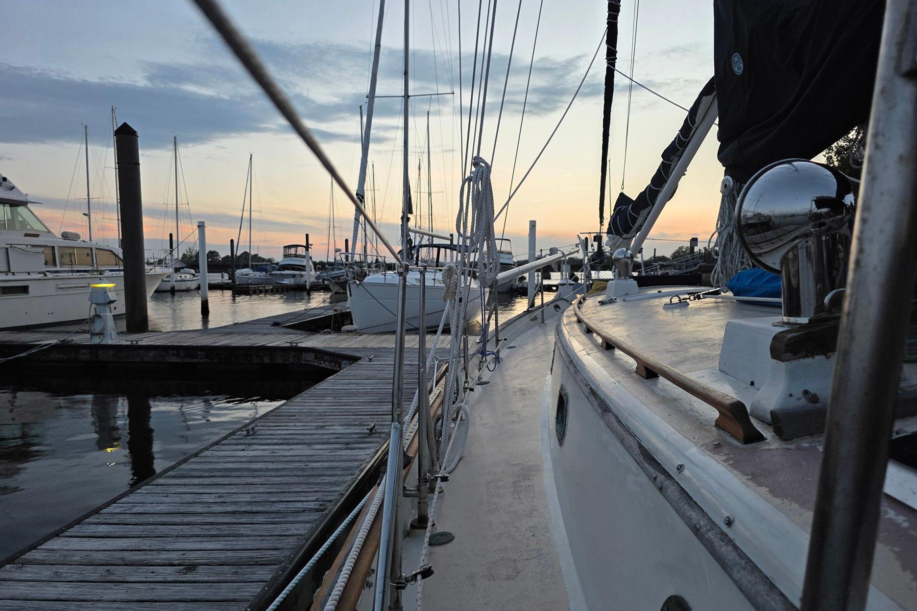 1982 Tayana 37 sailboat docked at marina during sunset, calm waters reflecting the sky.