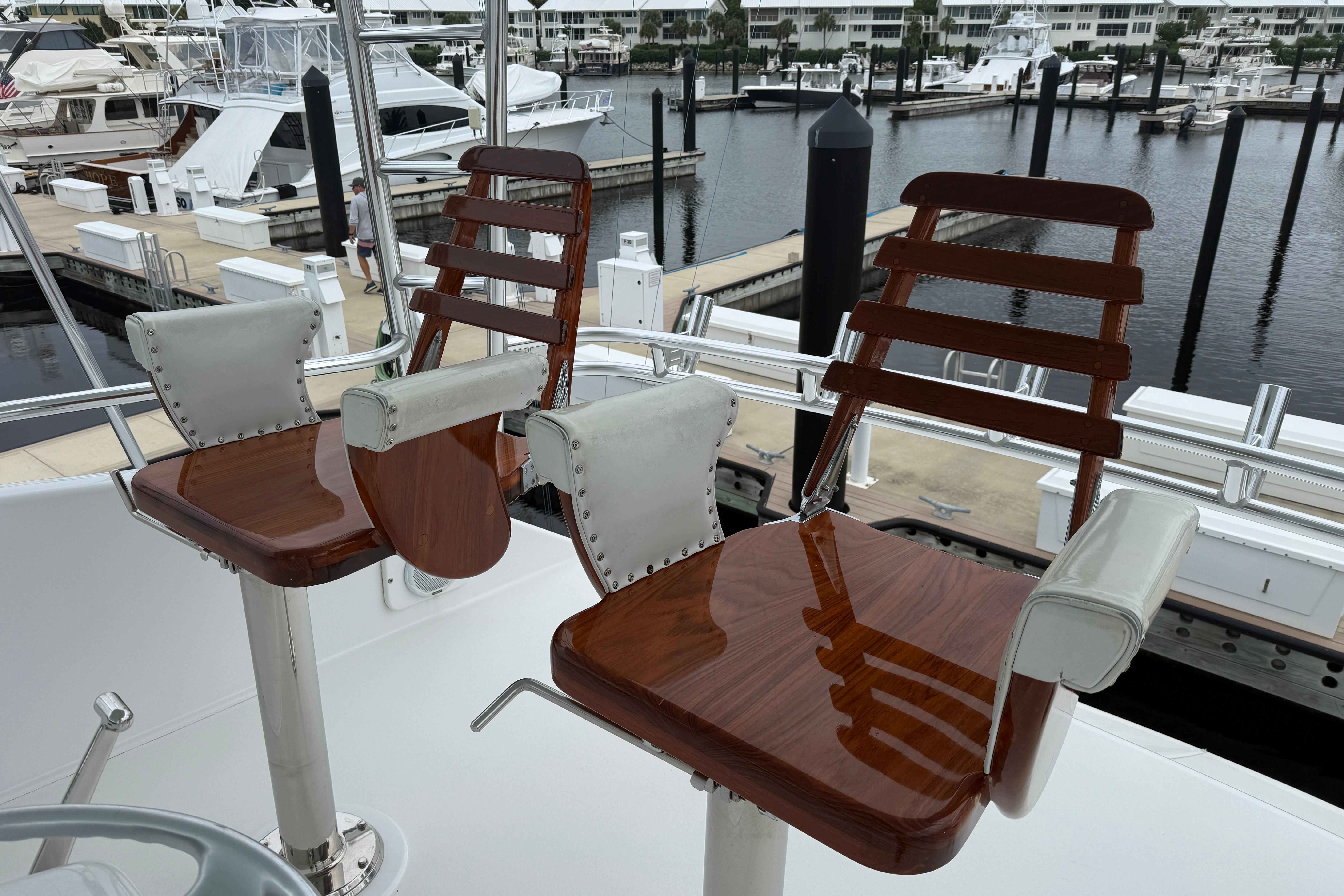 Luxury wooden helm chairs on a 2000 Viking 55 Convertible yacht at a marina.