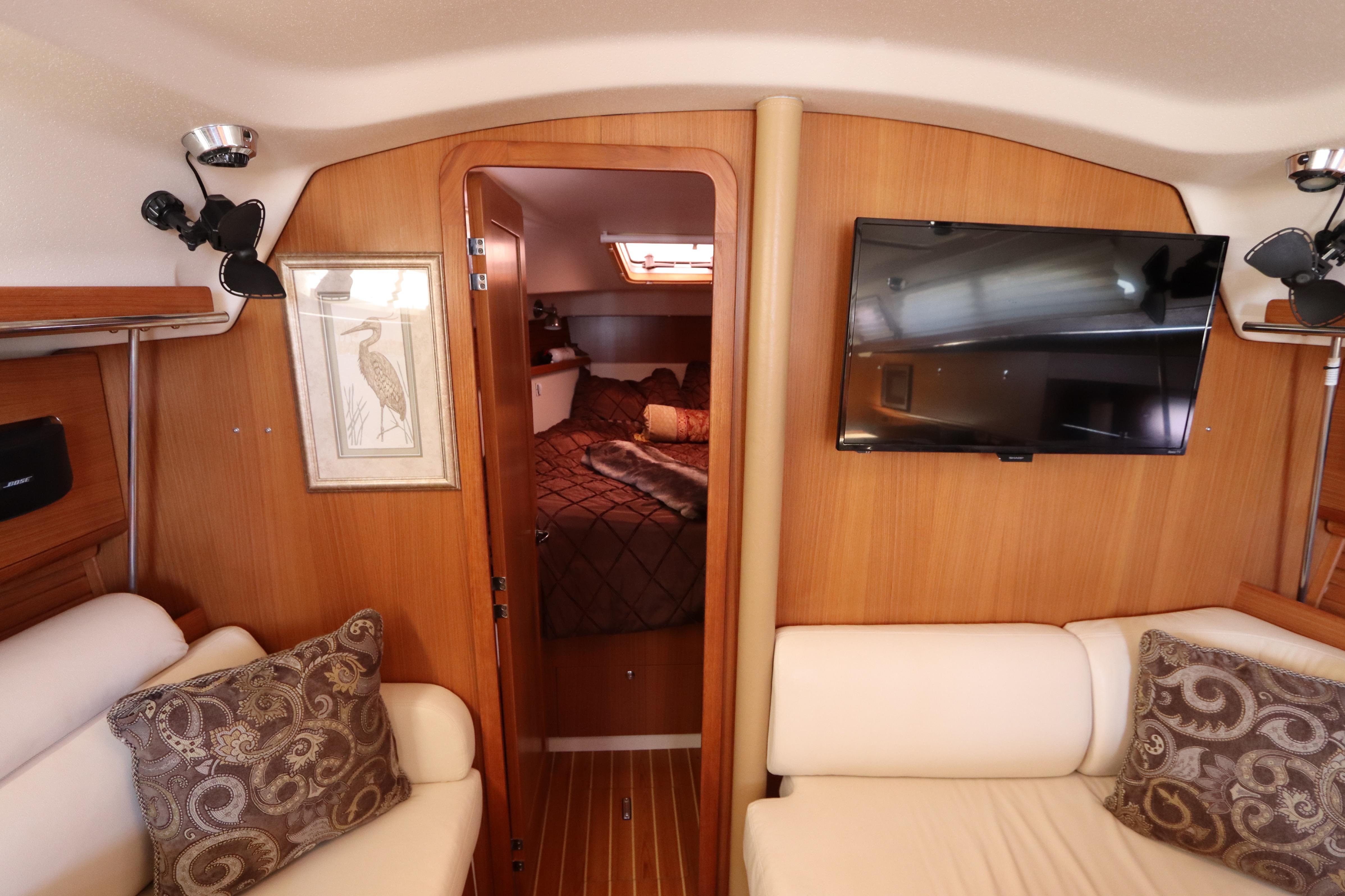 Interior of 2011 Catalina 355 yacht with cozy seating, wall art, and mounted TV.
