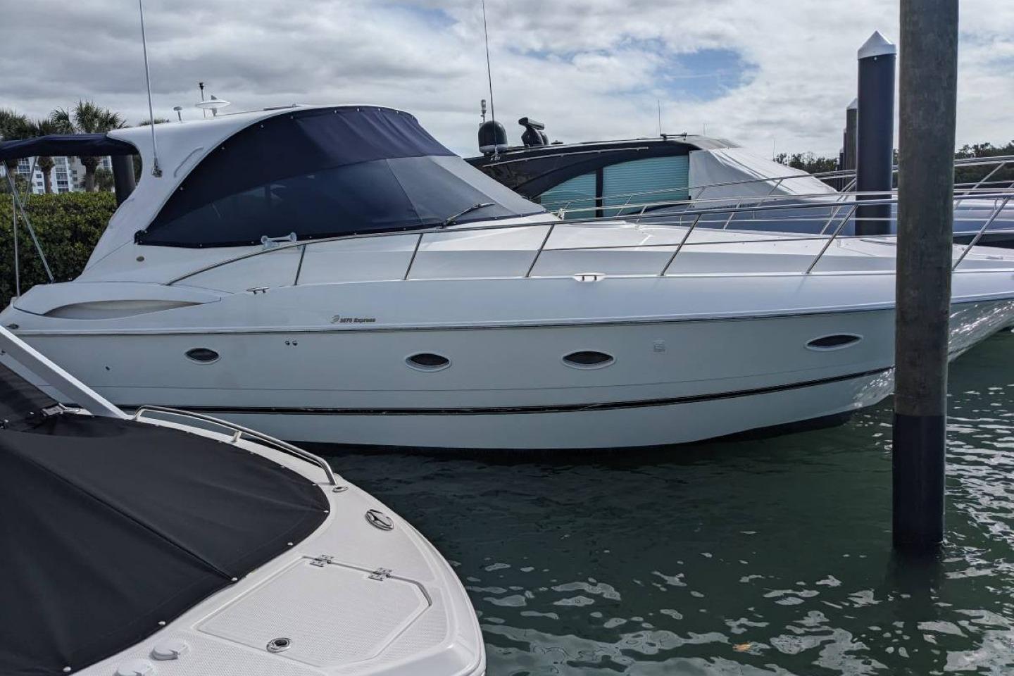 2003 Cruisers 3970 yacht docked in marina, featuring sleek white design and tinted windows.