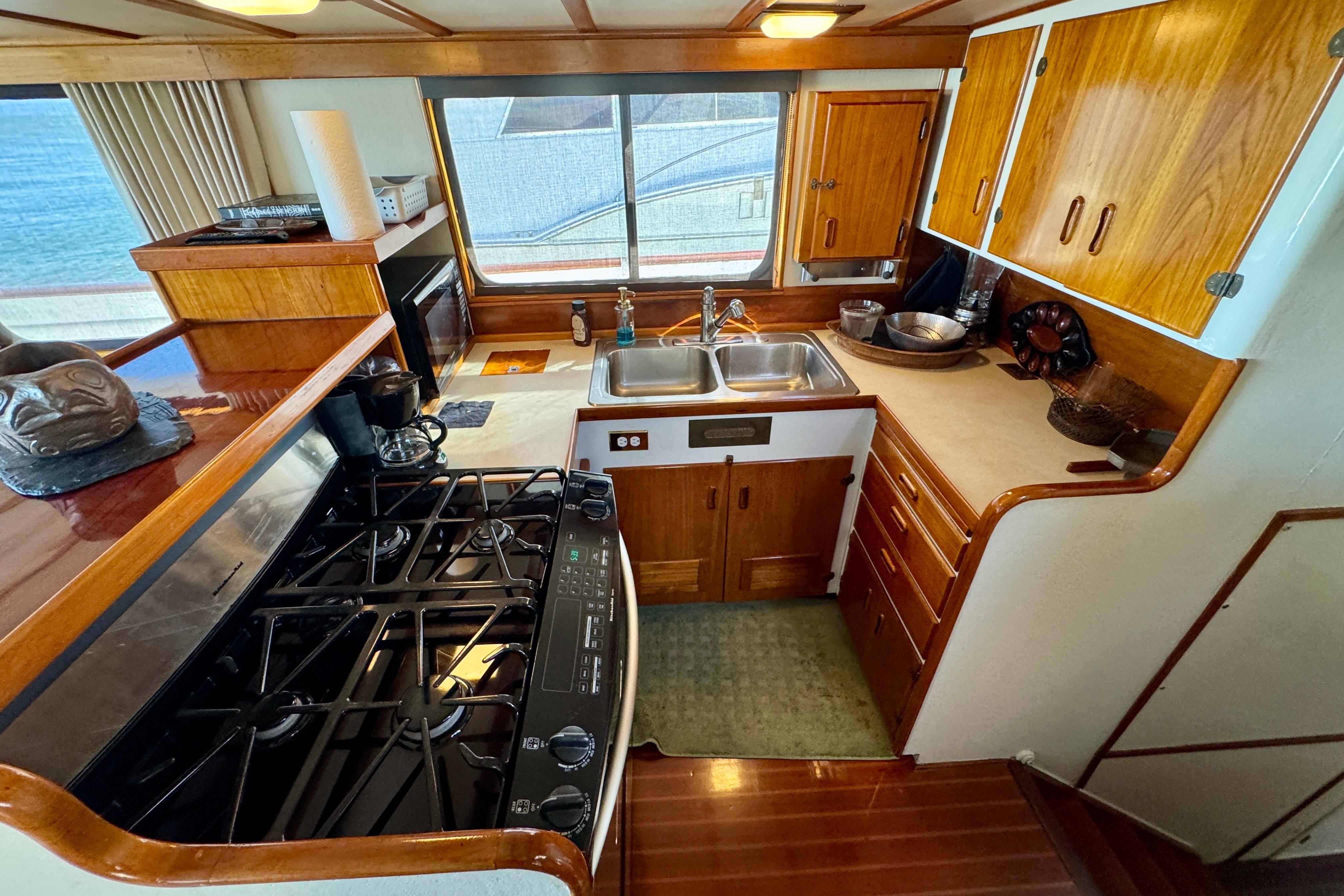 1958 Blanchard Pilothouse kitchen with wooden cabinets, stove, and dual sink.