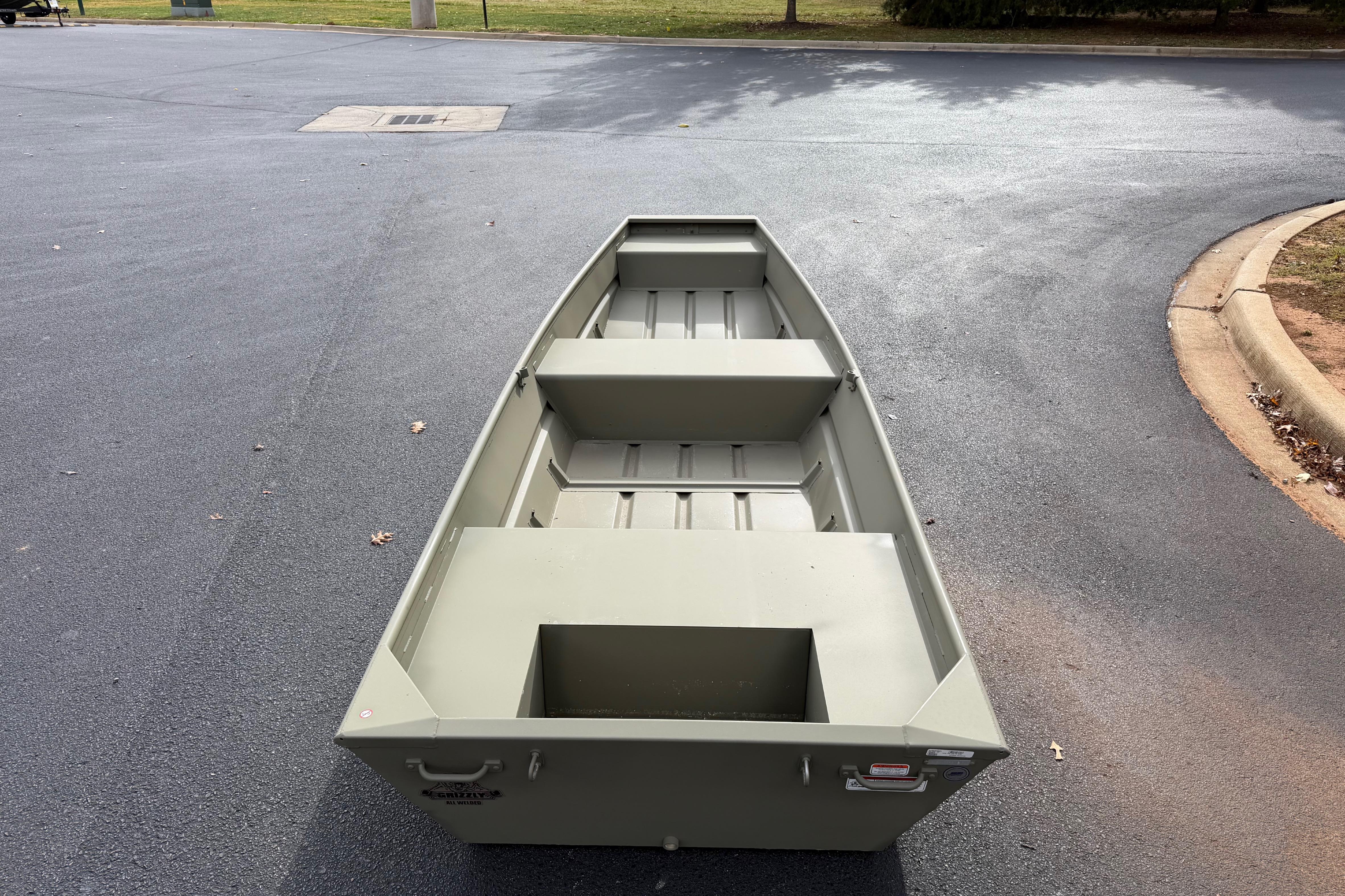 2025 Tracker Grizzly 1436 Utility boat on asphalt, showcasing its sturdy design.