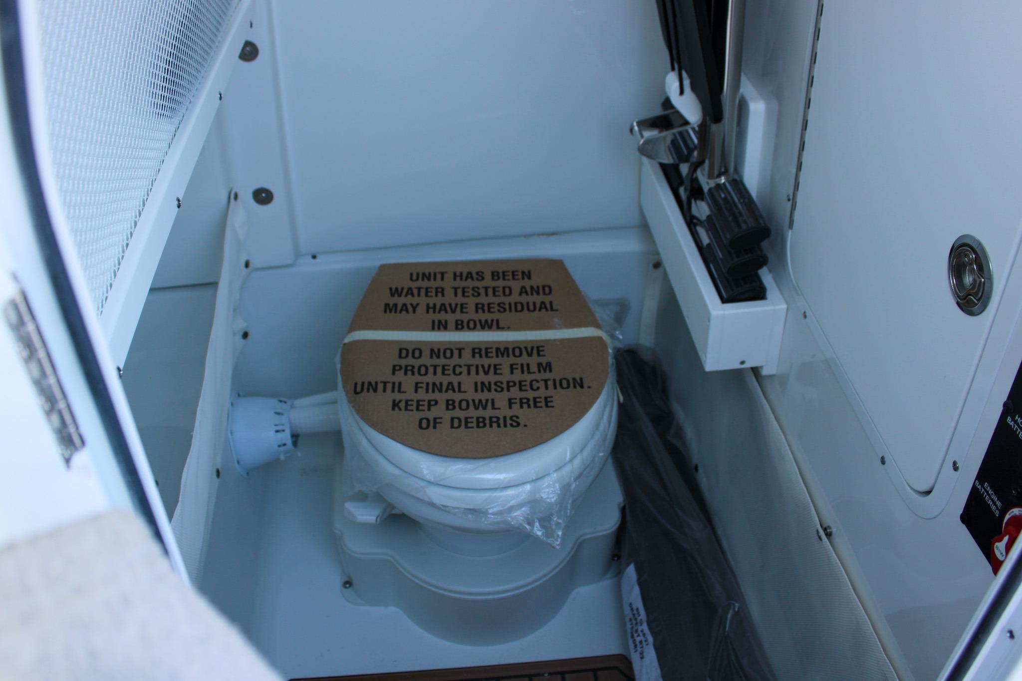 2026 Sea Hunt Gamefish 25 boat toilet with protective cover in compact cabin.