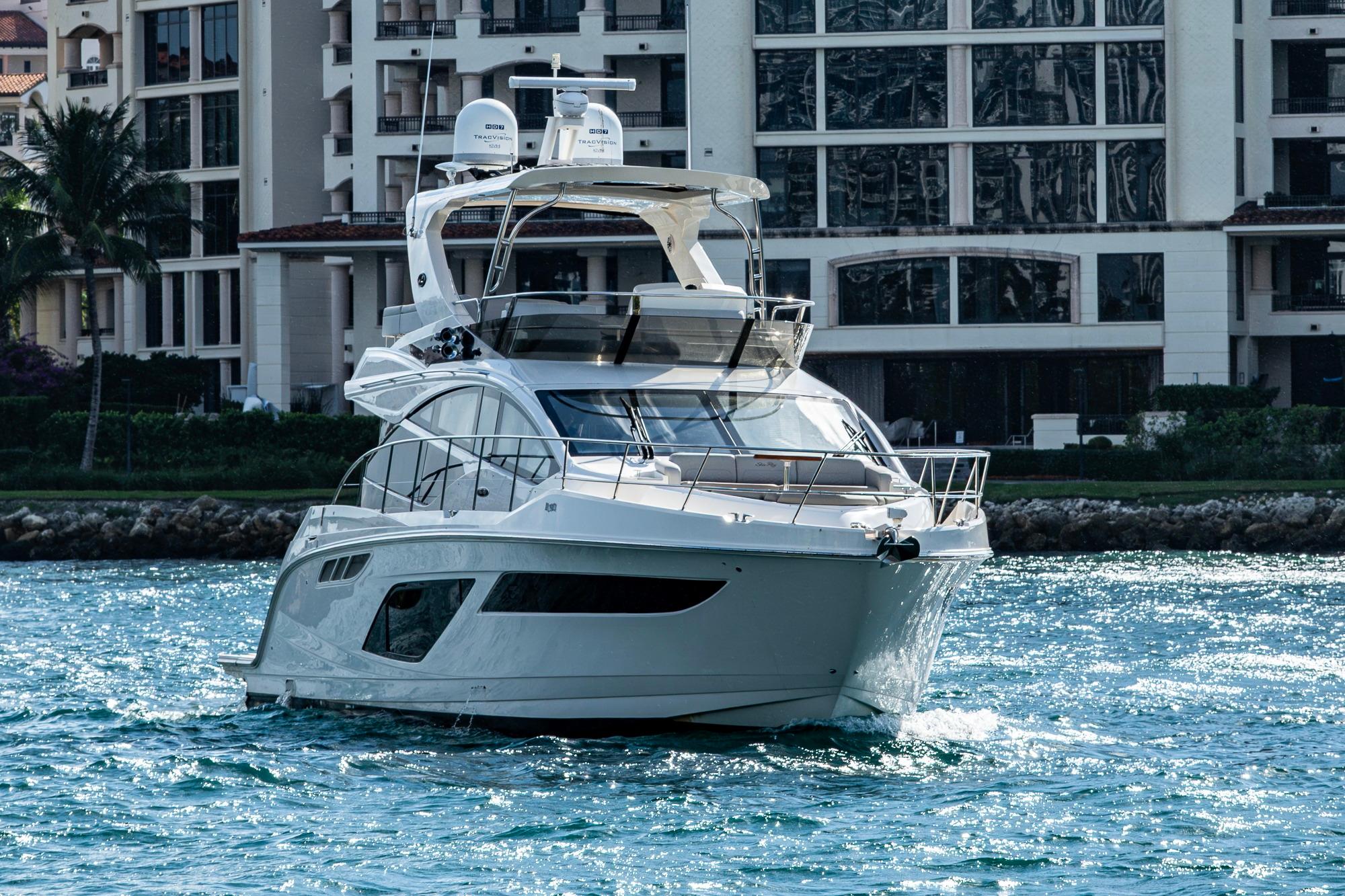 2018 Sea Ray L550 Fly yacht cruising near waterfront buildings.