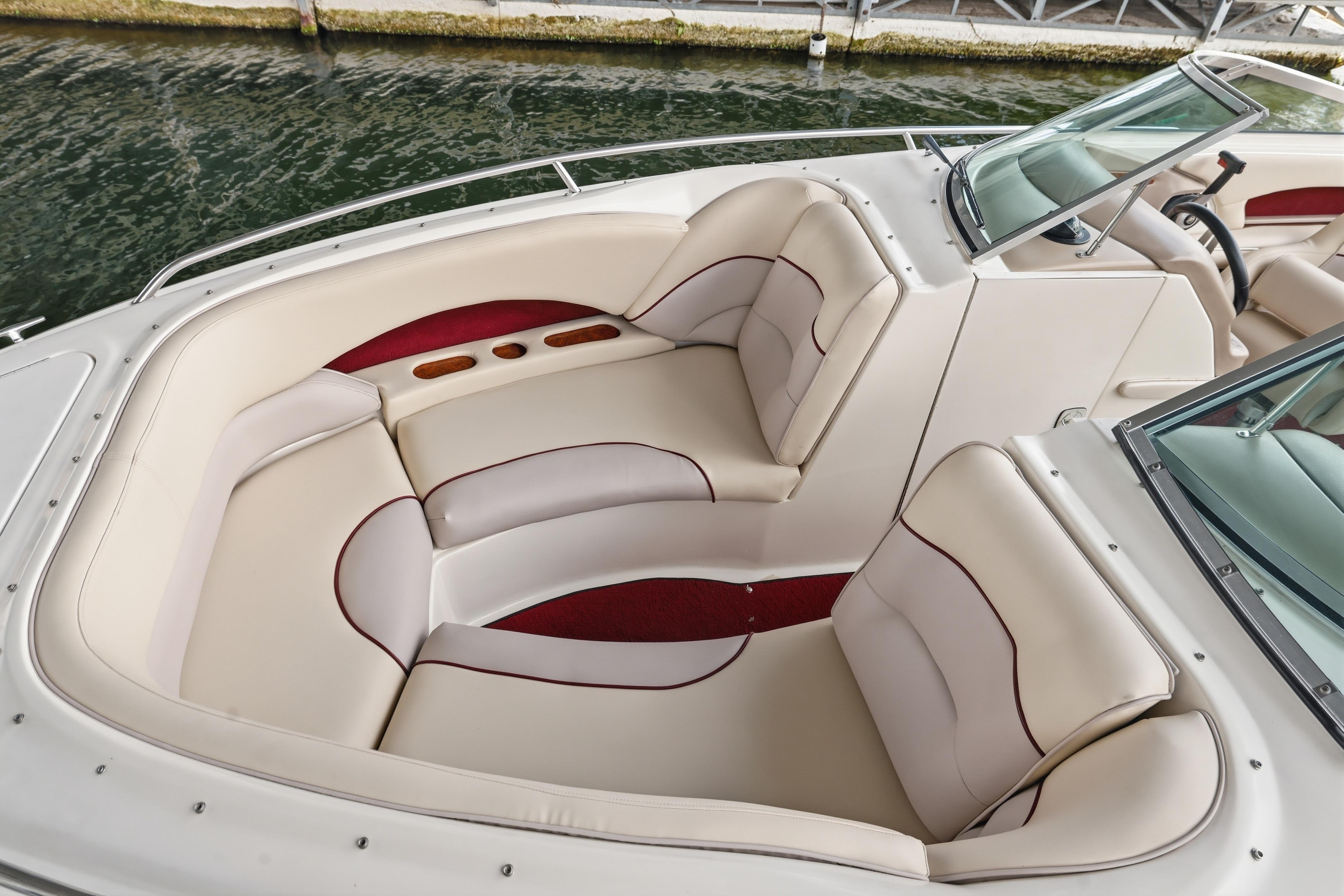 1997 Sea Ray 230 Signature boat interior with cream and red seating, docked by water.