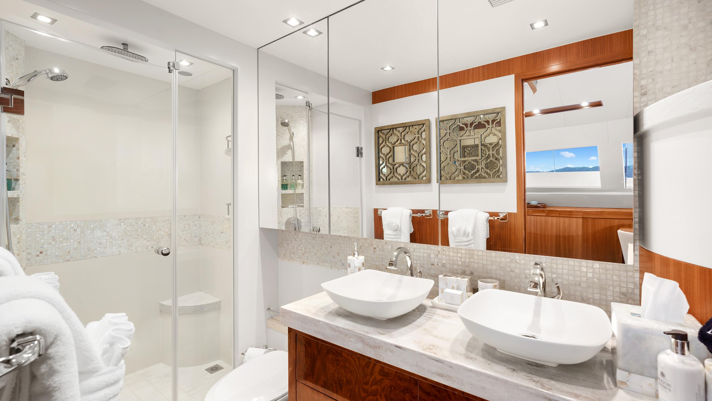 Luxurious yacht bathroom with dual sinks, glass shower, and elegant decor on Horizon PC74, 2018 model.