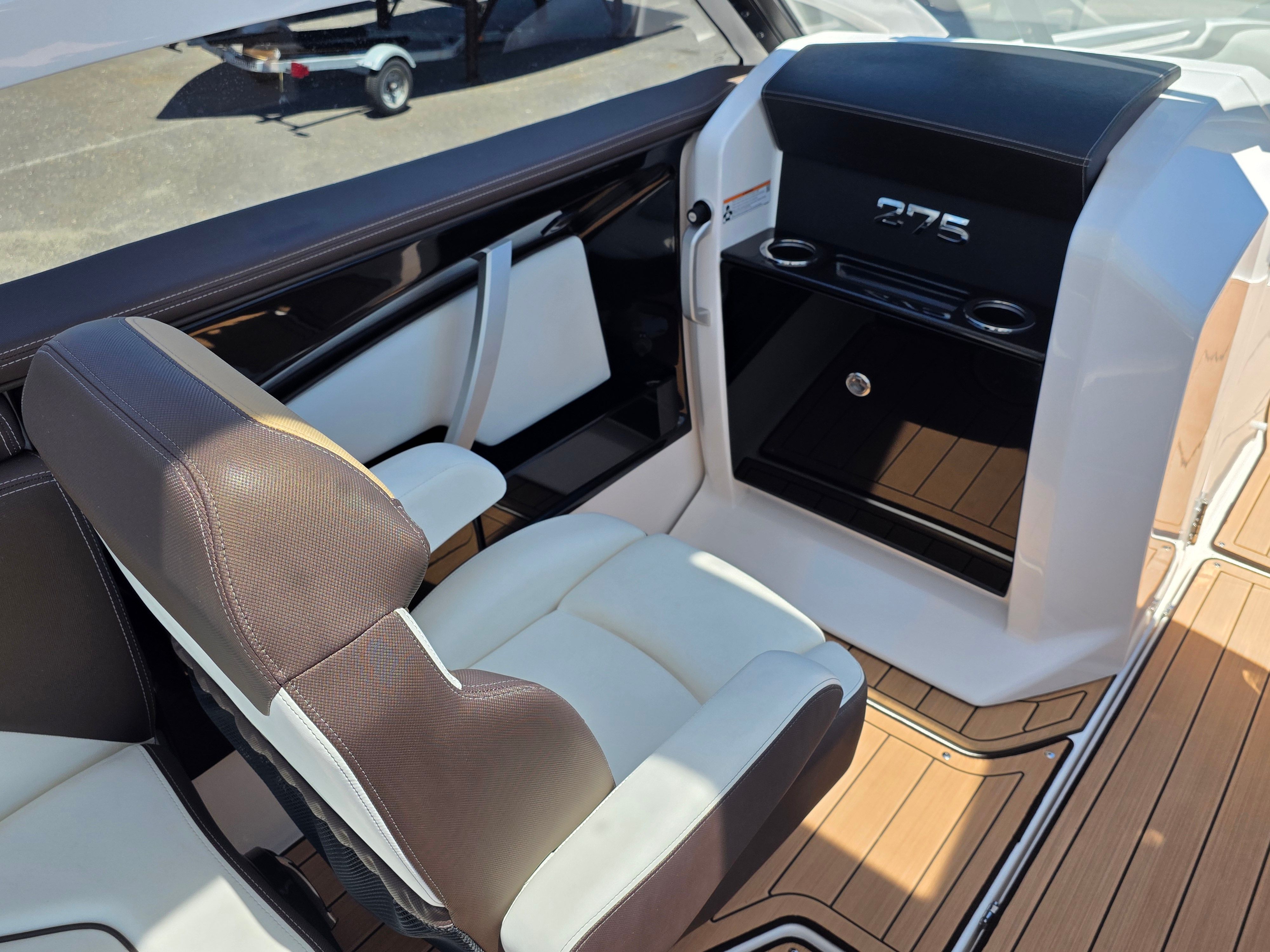 The image shows the interior of a 2023 Yamaha Boats sd275 with sleek seating and wood flooring.