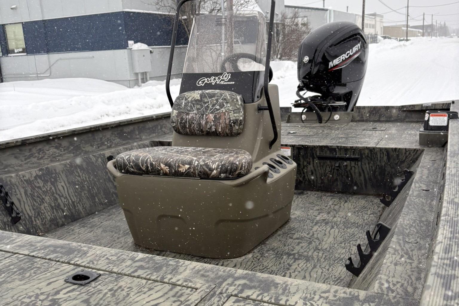2025 Tracker Grizzly 2072 CC boat with camo seating and Mercury outboard motor in snowy setting.