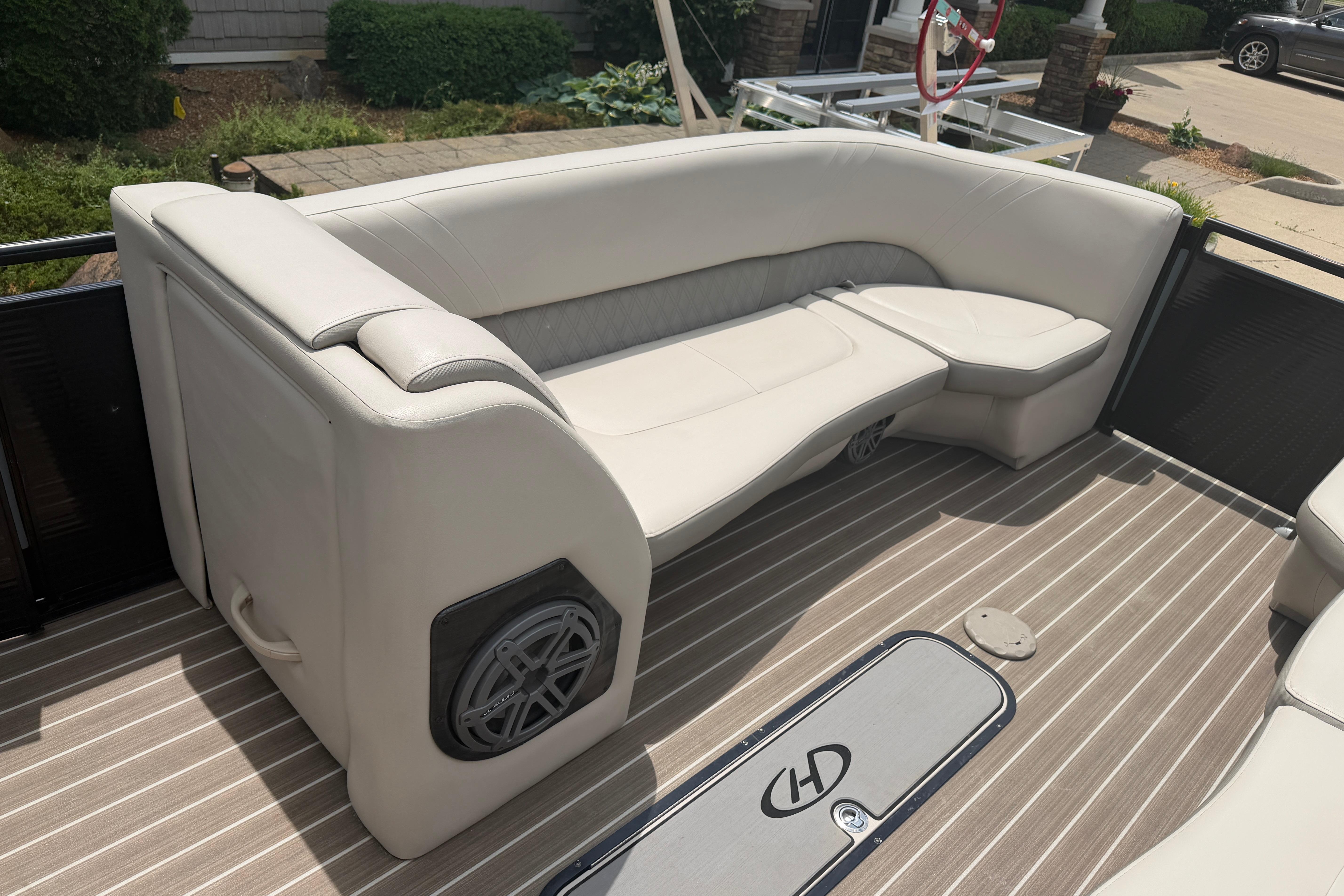 Luxurious seating on 2019 Harris Solstice 240 boat with beige upholstery and striped flooring.