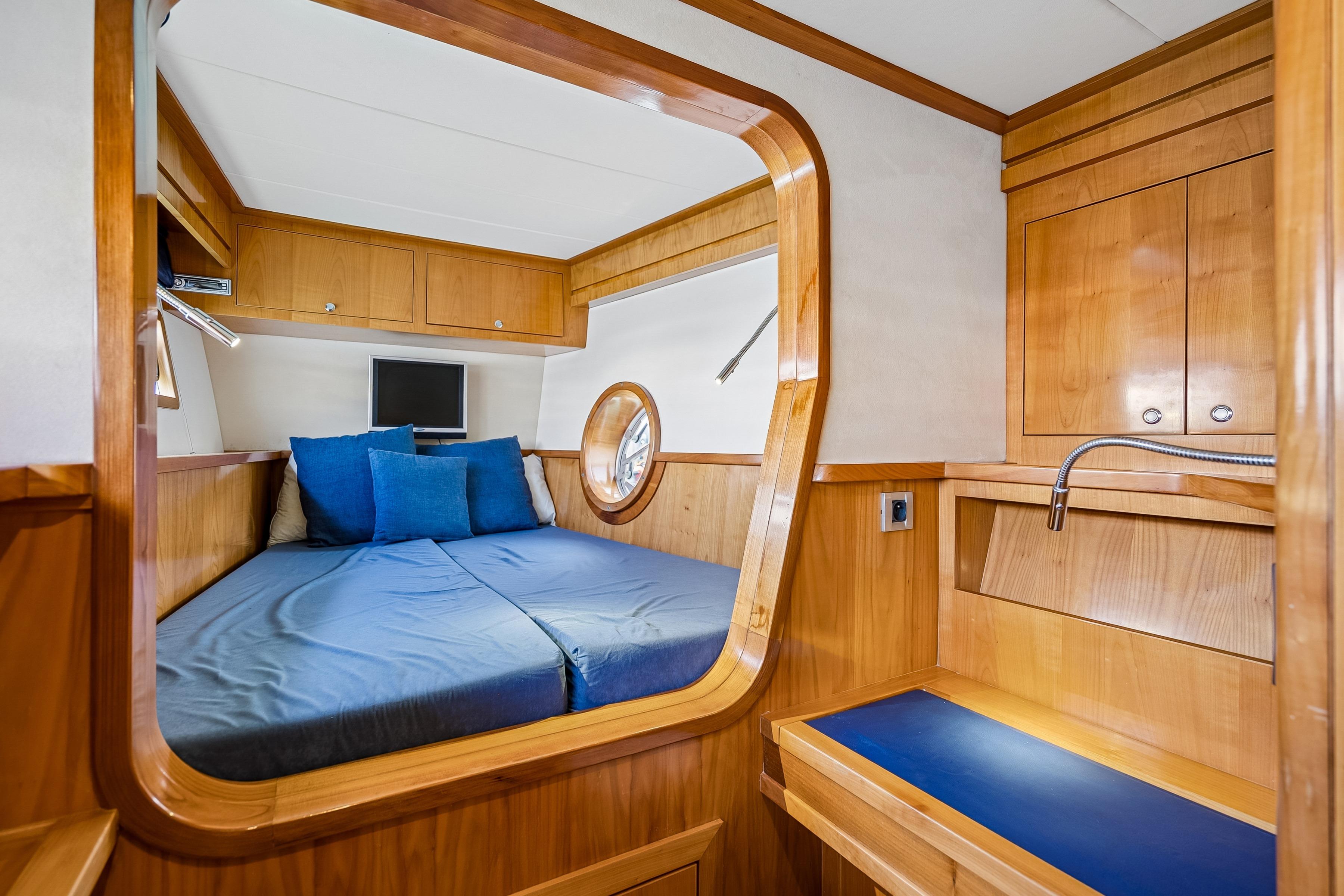 Luxurious wooden cabin interior of 2009 Catana 65 yacht with cozy bed and porthole.