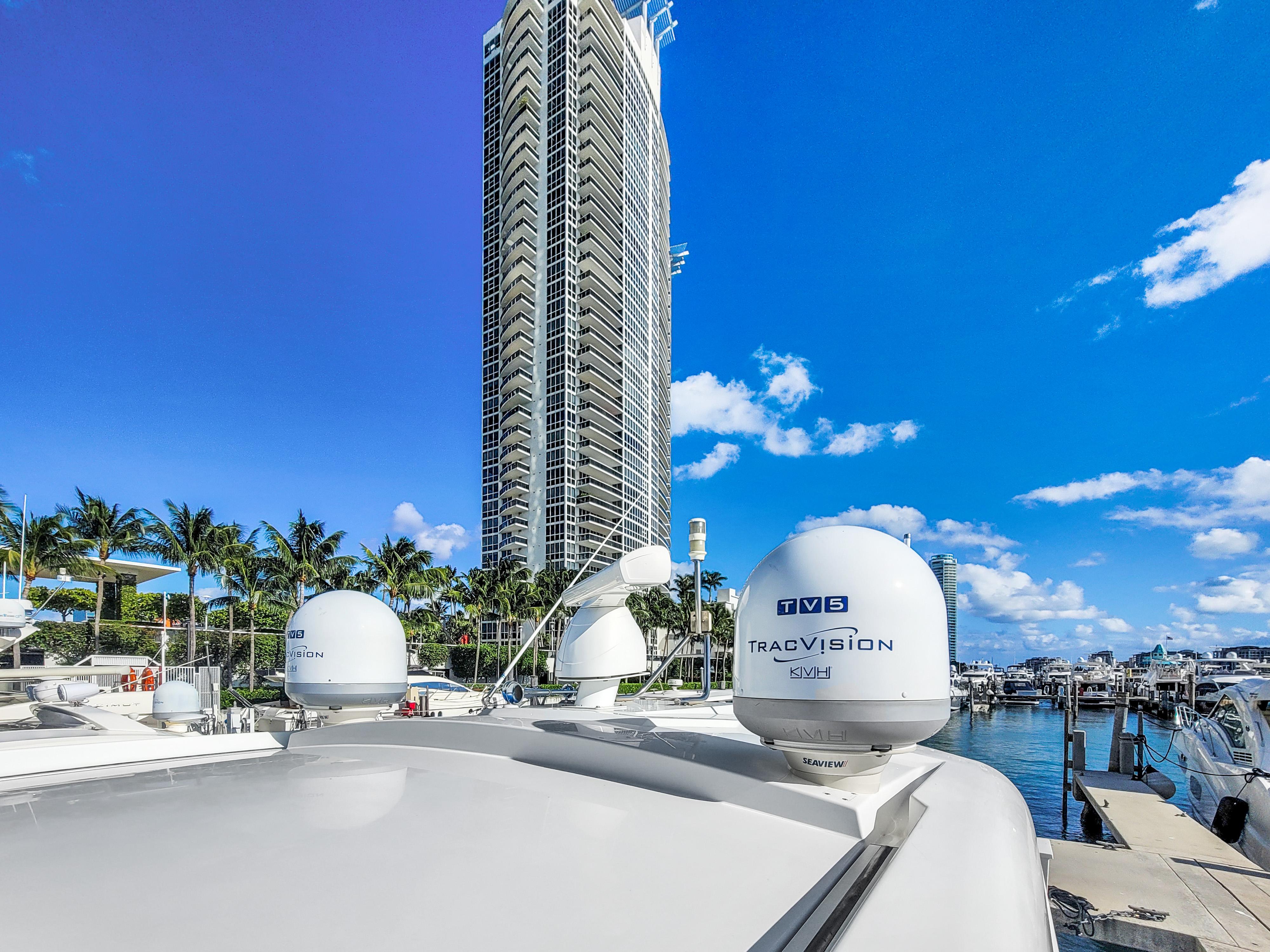 2019 Cruisers 50 Cantius yacht docked near a tall building and palm trees.