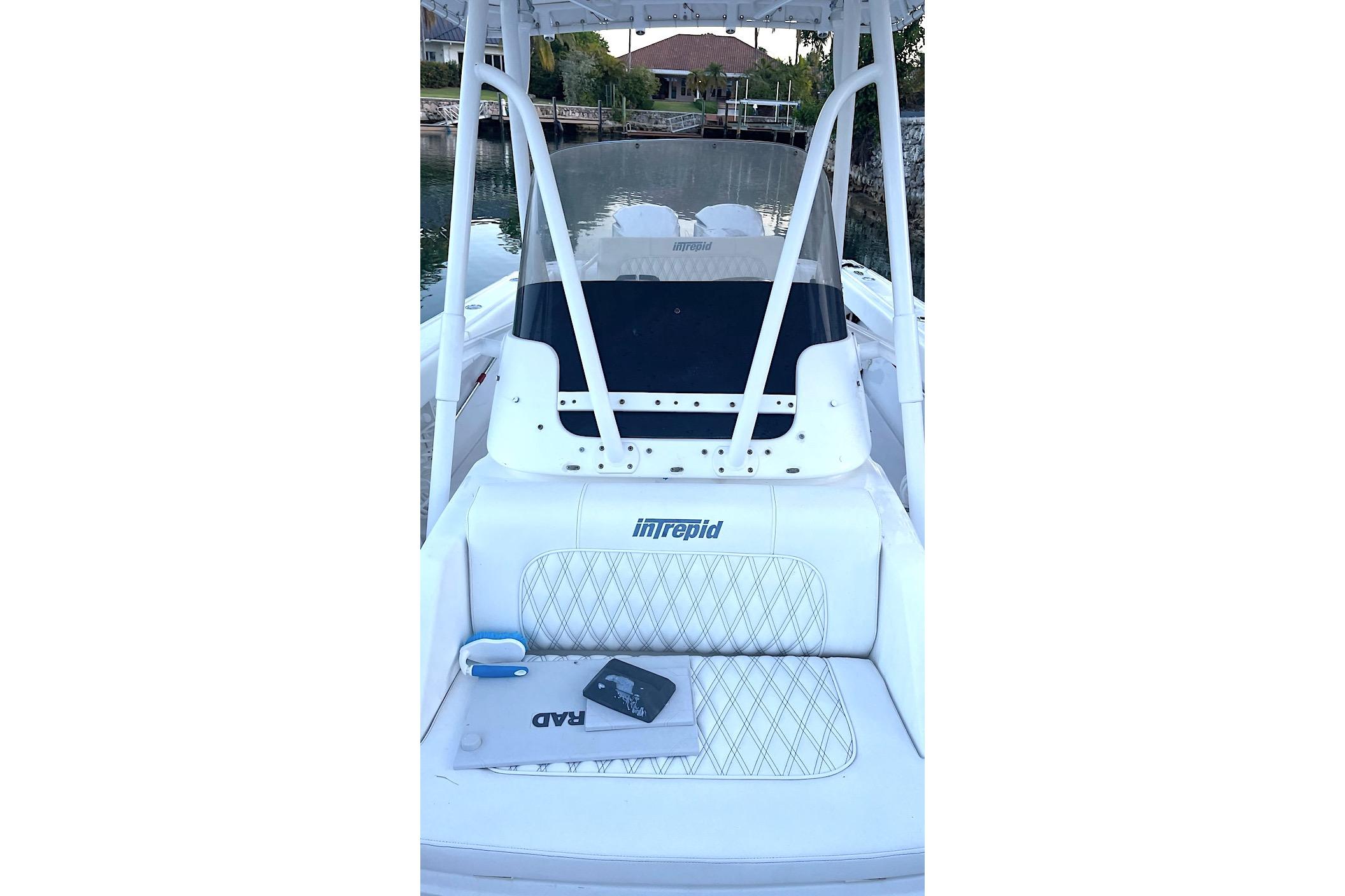 2002 Intrepid 323 Cuddy boat interior with seating and console, docked by waterfront homes.