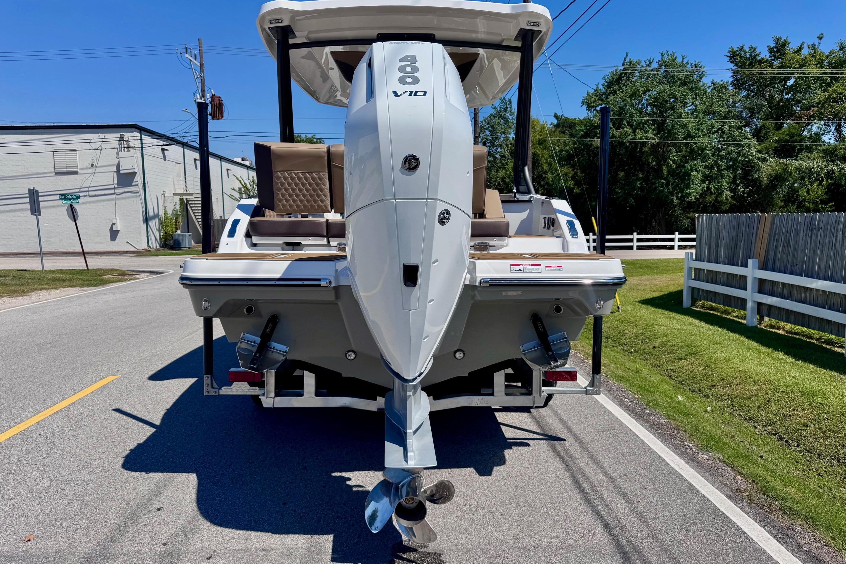 2026 Monterey Elite 27 OB boat with powerful outboard motor on a sunny street.