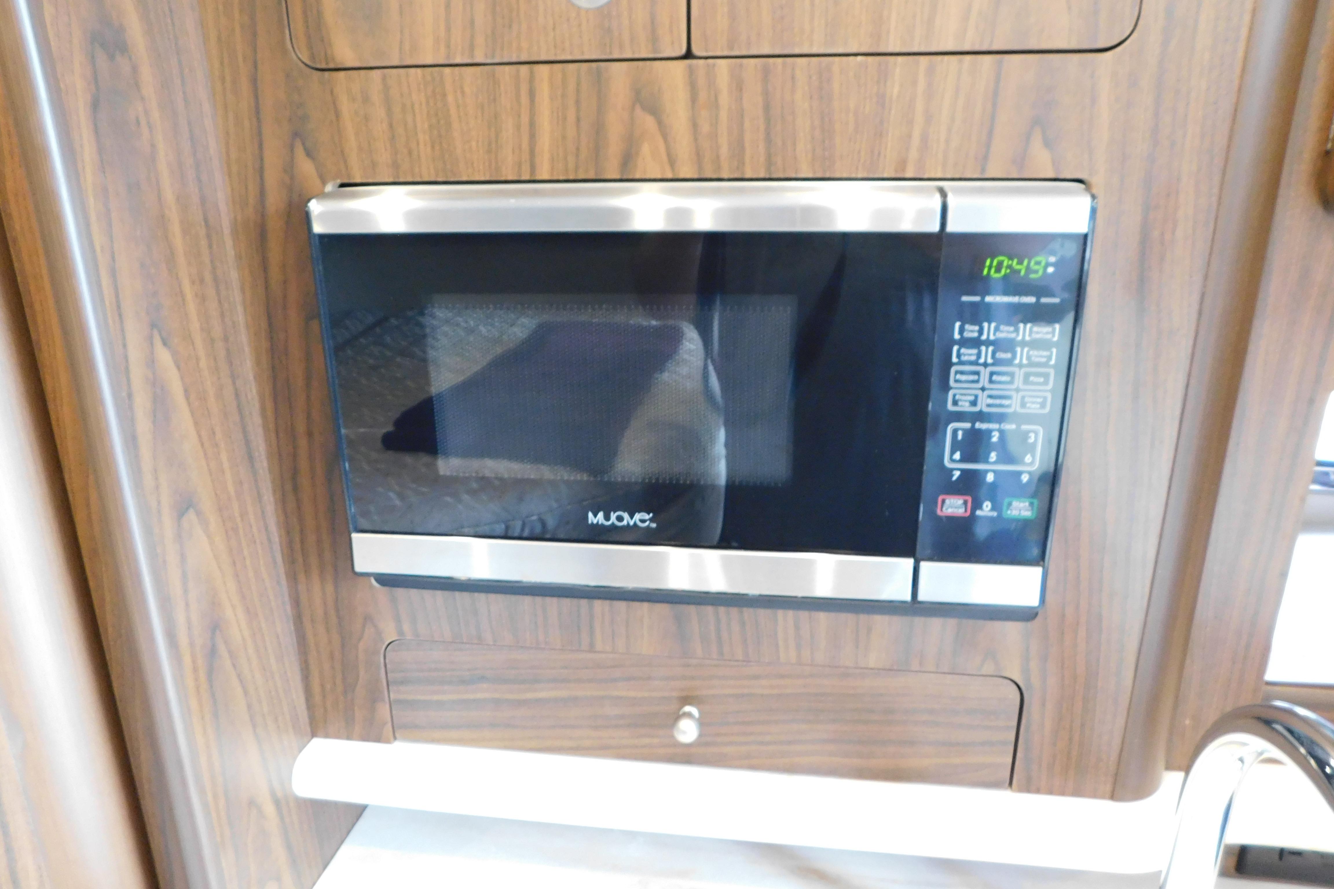 Built-in microwave in 2017 Rinker EX 320 boat interior, wood paneling background.