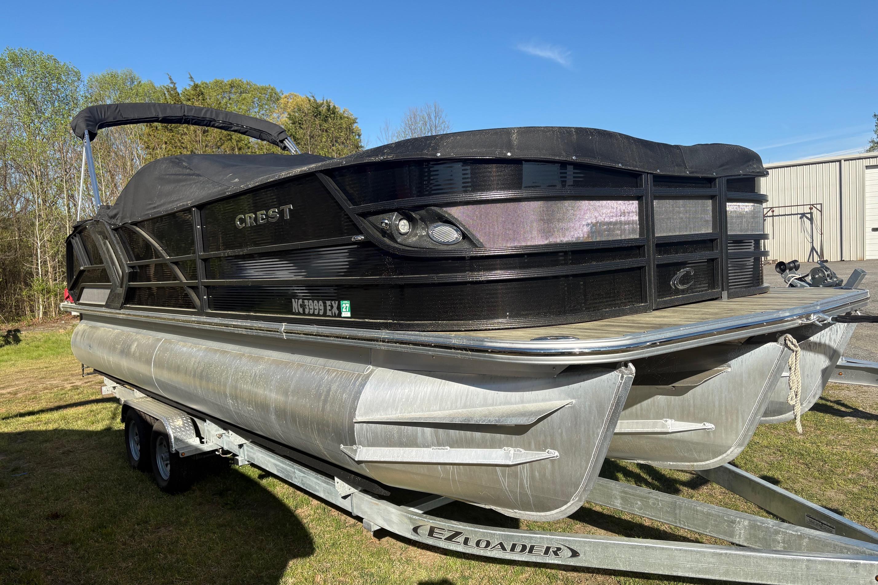 2022 Crest Continental 250 pontoon boat on trailer, covered and parked outdoors.