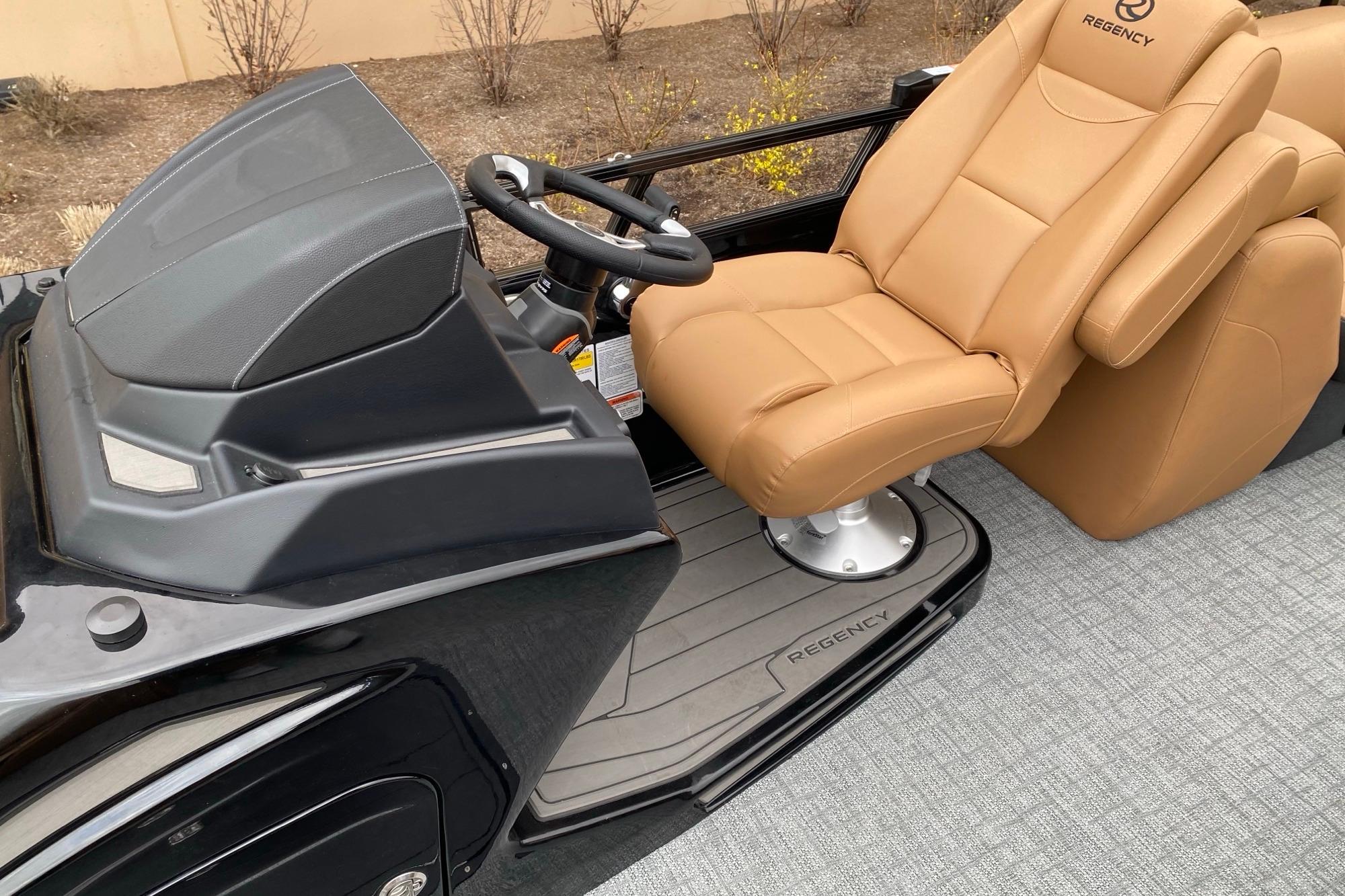Luxurious 2026 Regency 230 DL boat interior with tan leather captain's chair and sleek dashboard.