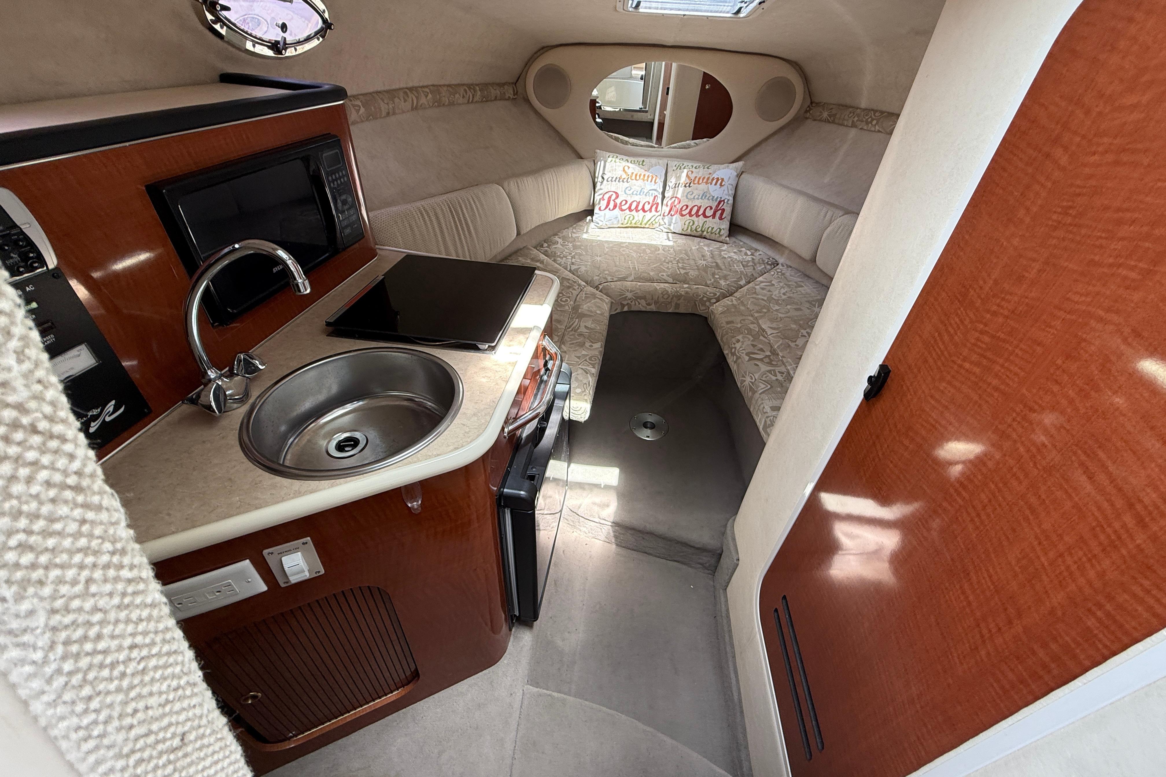 2004 Sea Ray 240 Sundancer cabin interior with kitchenette and cozy seating area.