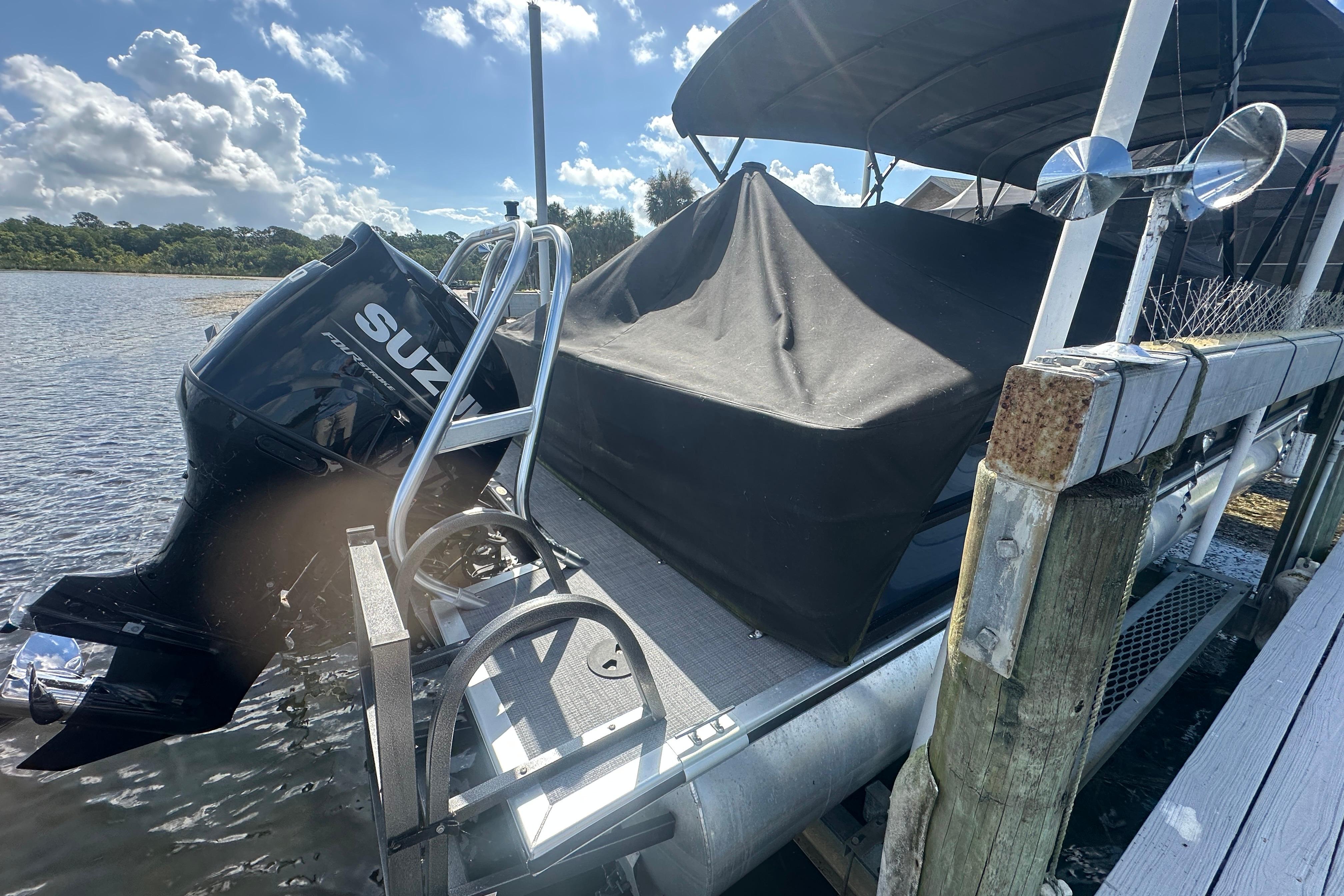 2023 Bentley Pontoons Legacy 243 Swingback docked with Suzuki engine, covered and secured.