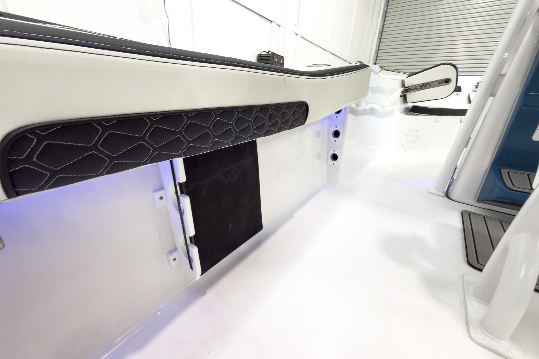 Interior view of a boat with white and black upholstery and blue lighting.