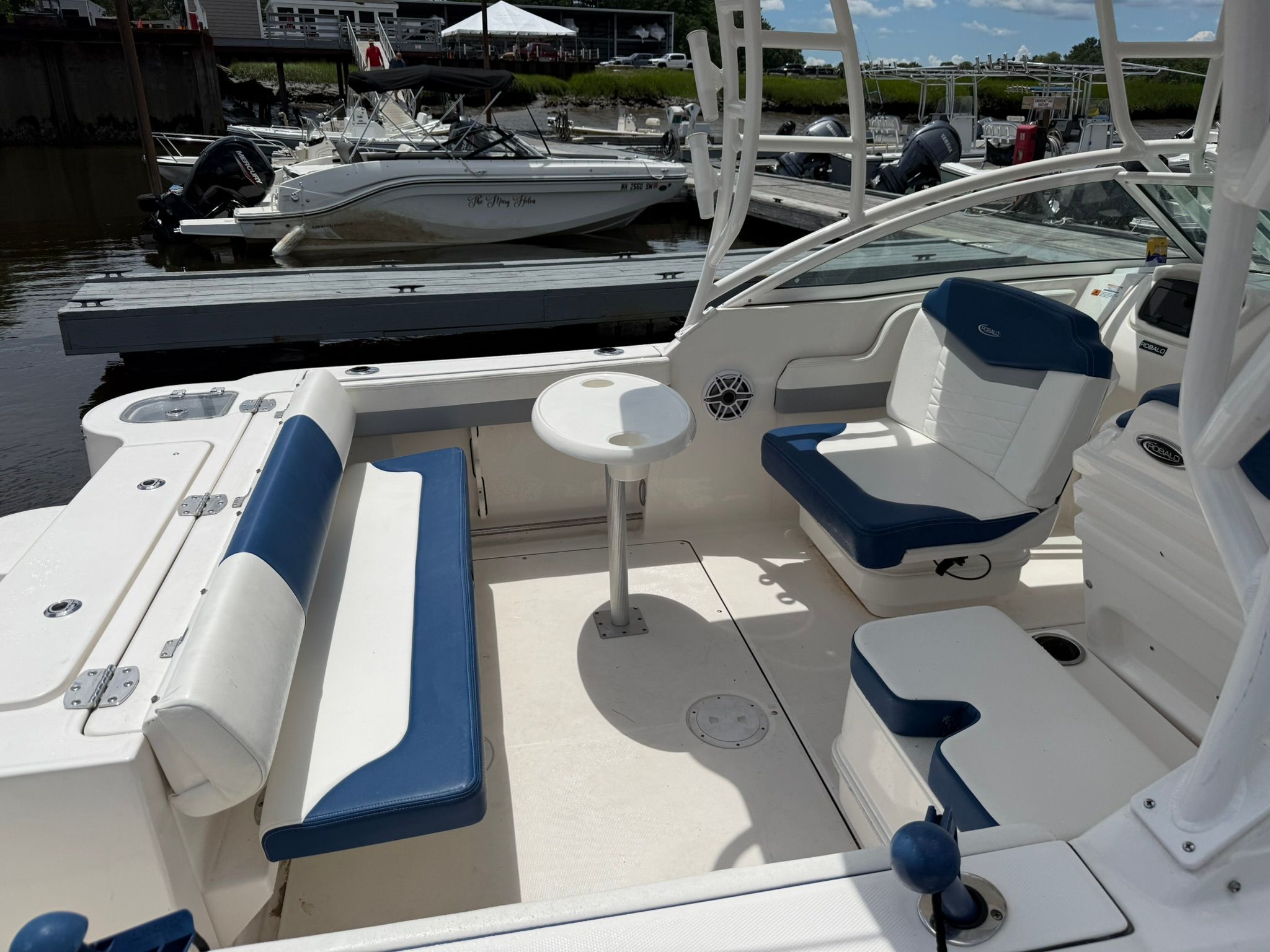 The image shows the cockpit of a Robalo R247 Dual Console boat with blue and white seating.