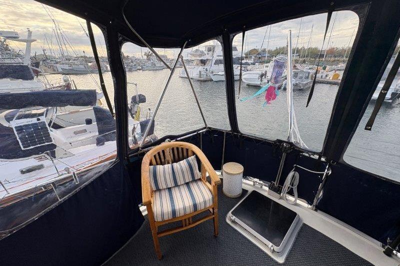1987 Tollycraft 34 Sundeck Motor Yacht interior with marina view, featuring a striped chair.