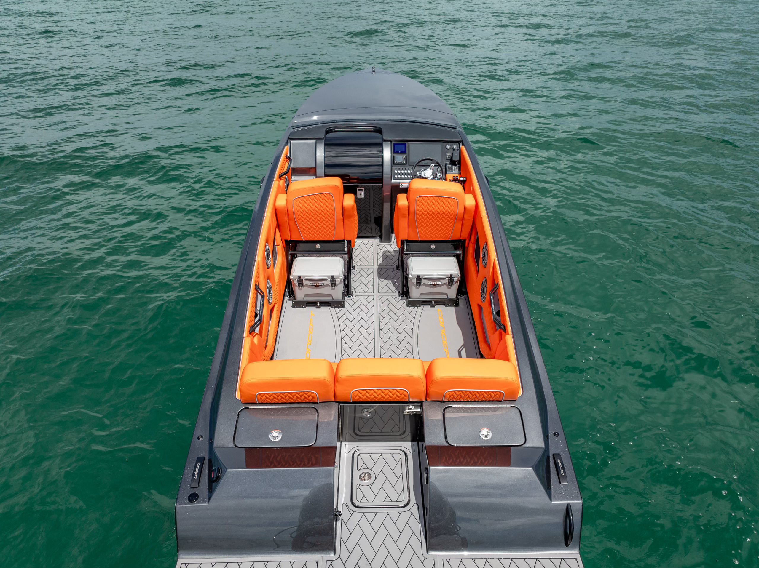 The image shows a modern sport boat with orange seating on calm water.