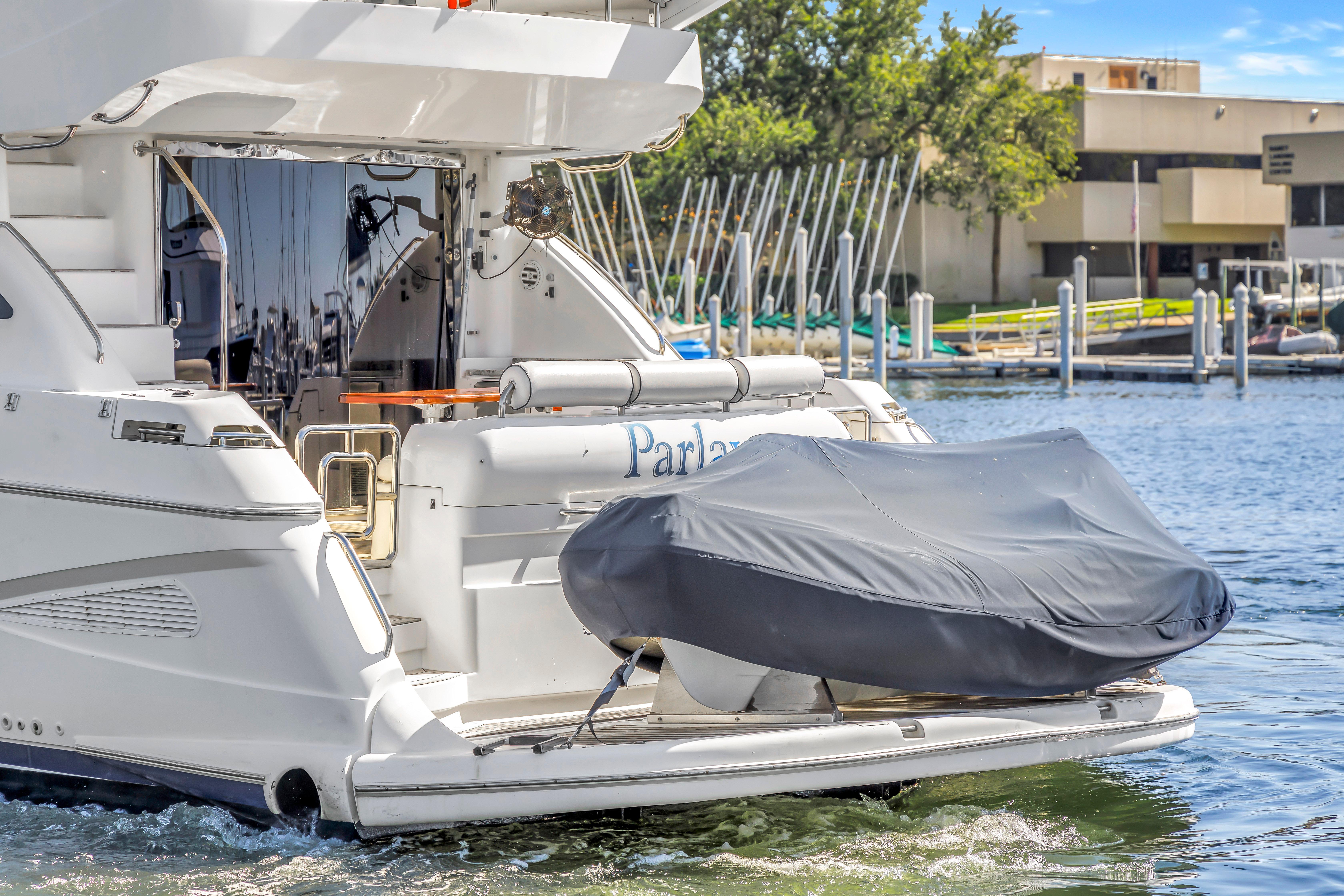 2001 Neptunus 56 Flybridge yacht docked with covered tender at marina.