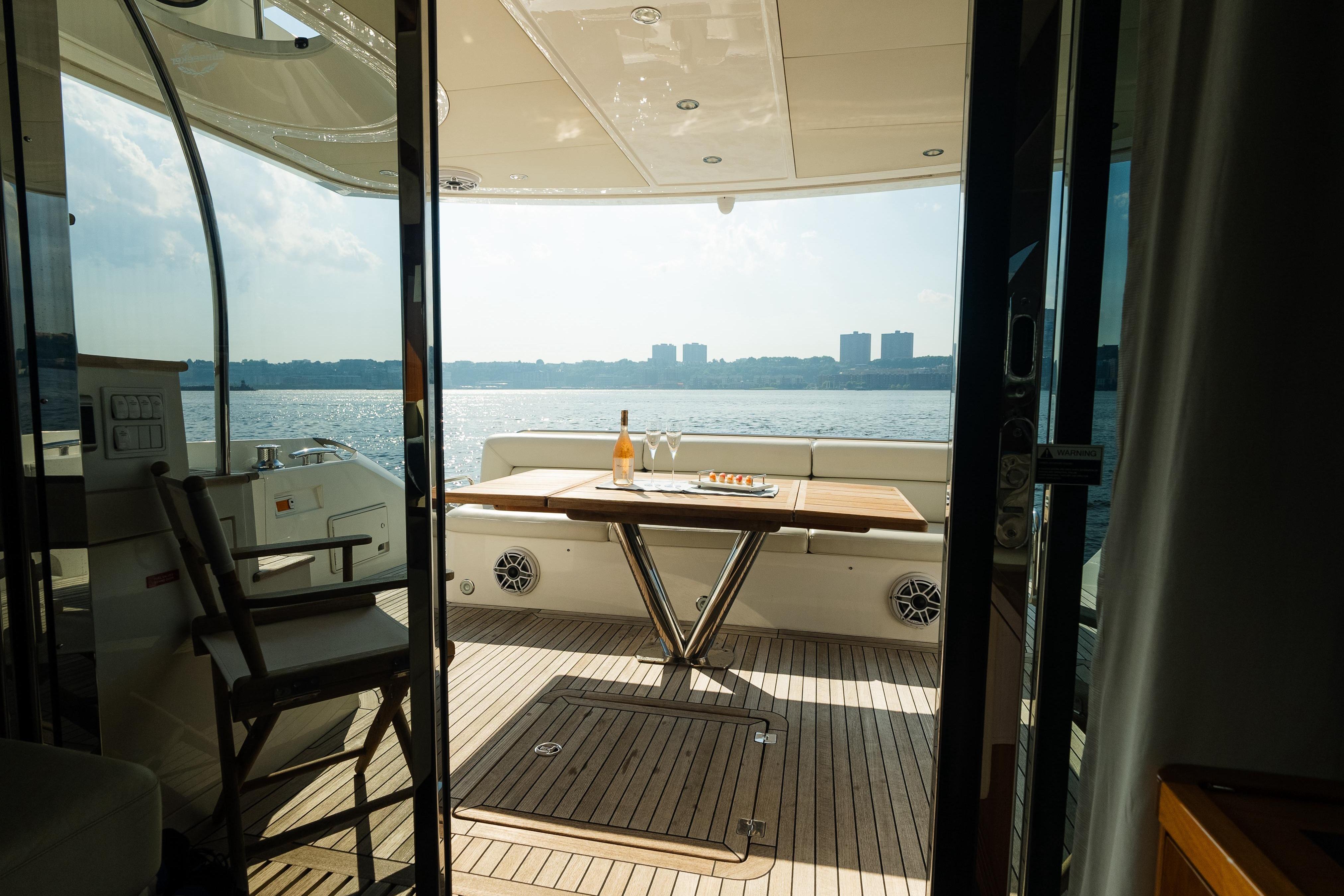 Luxurious Sunseeker Manhattan 65 yacht deck with table, chairs, and waterfront view.