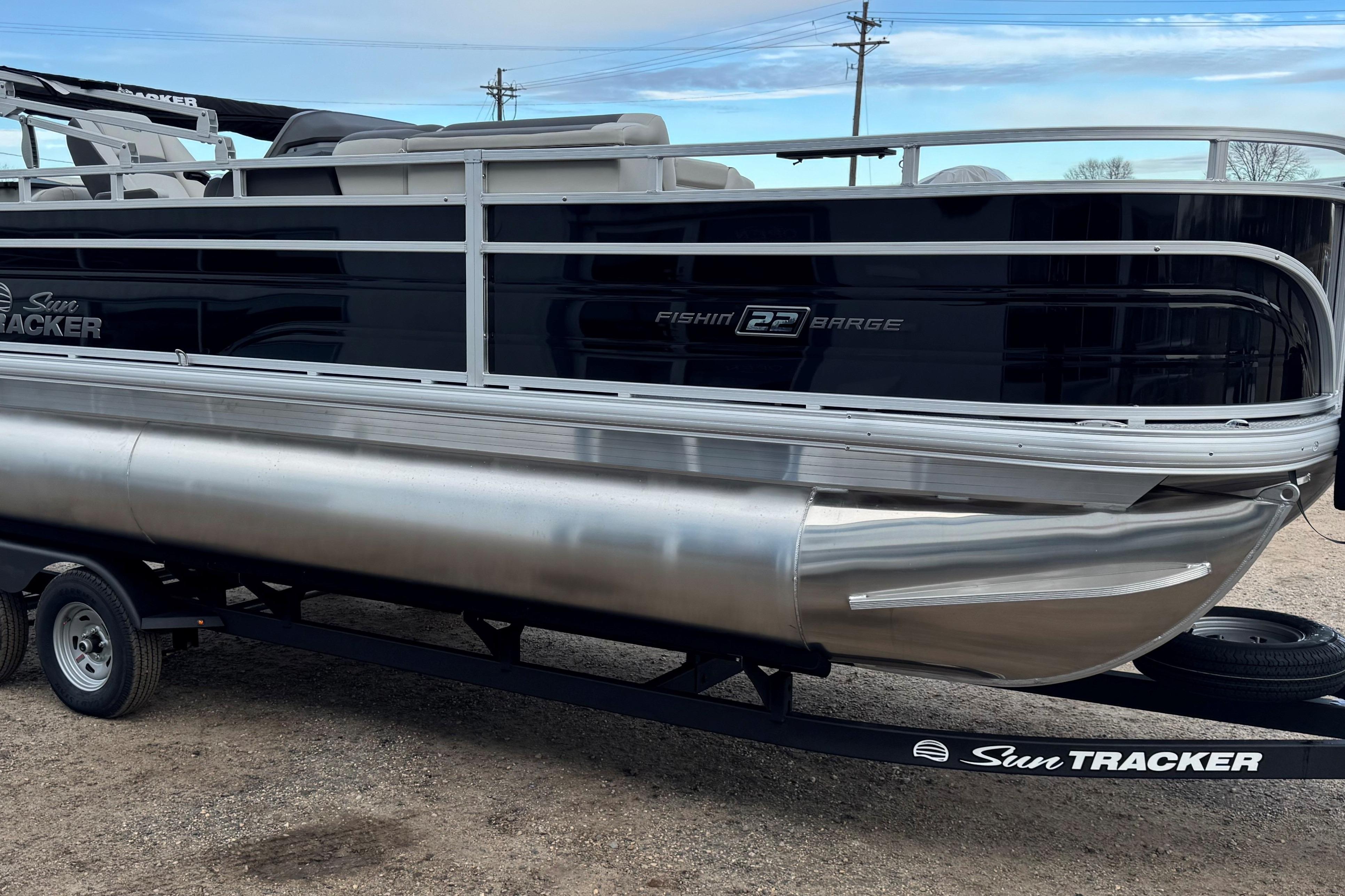 2026 Sun Tracker Fishin' Barge 22 DLX pontoon boat on trailer, side view.