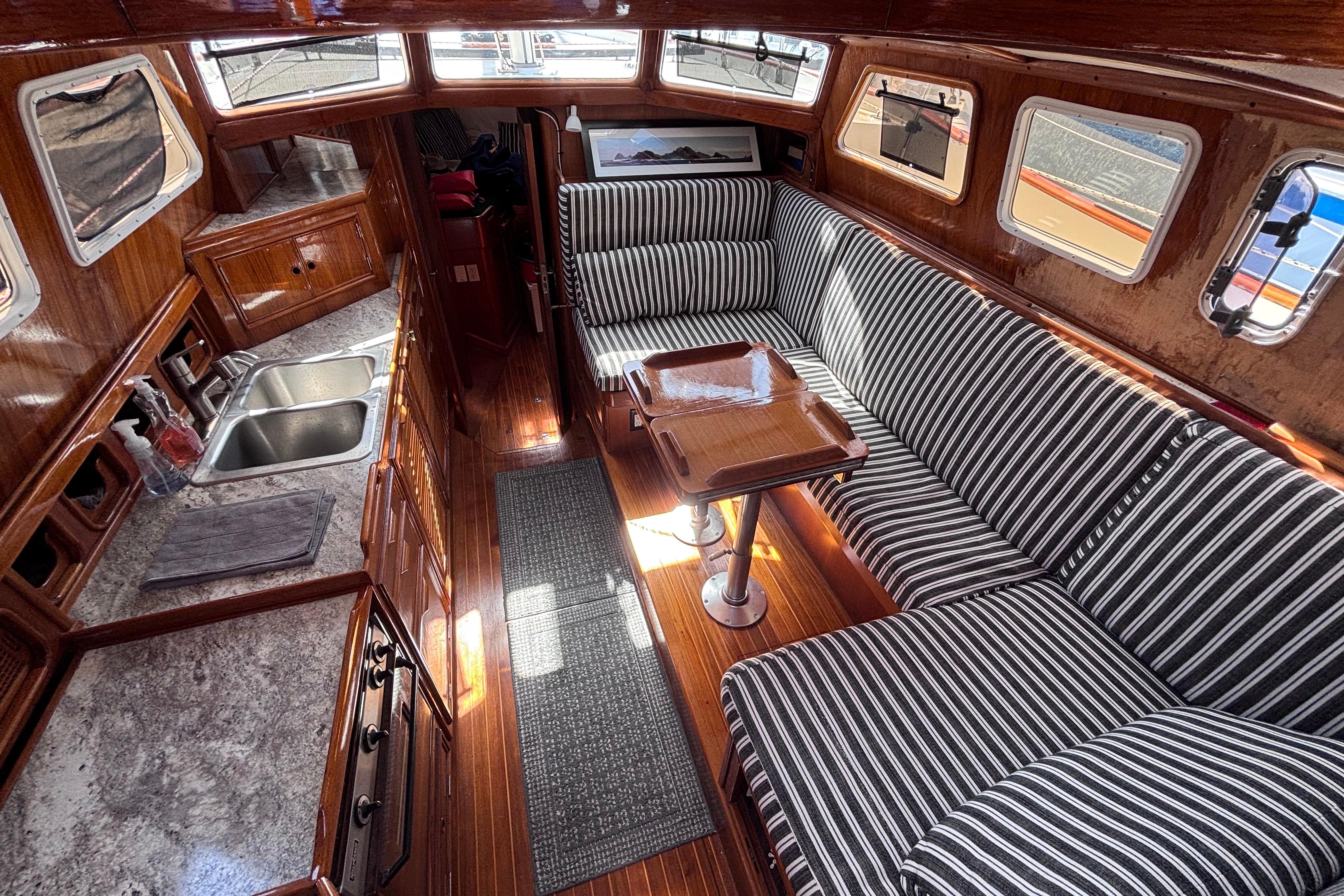 1978 Swift 33 yacht interior with striped seating, wooden finishes, and compact kitchen area.