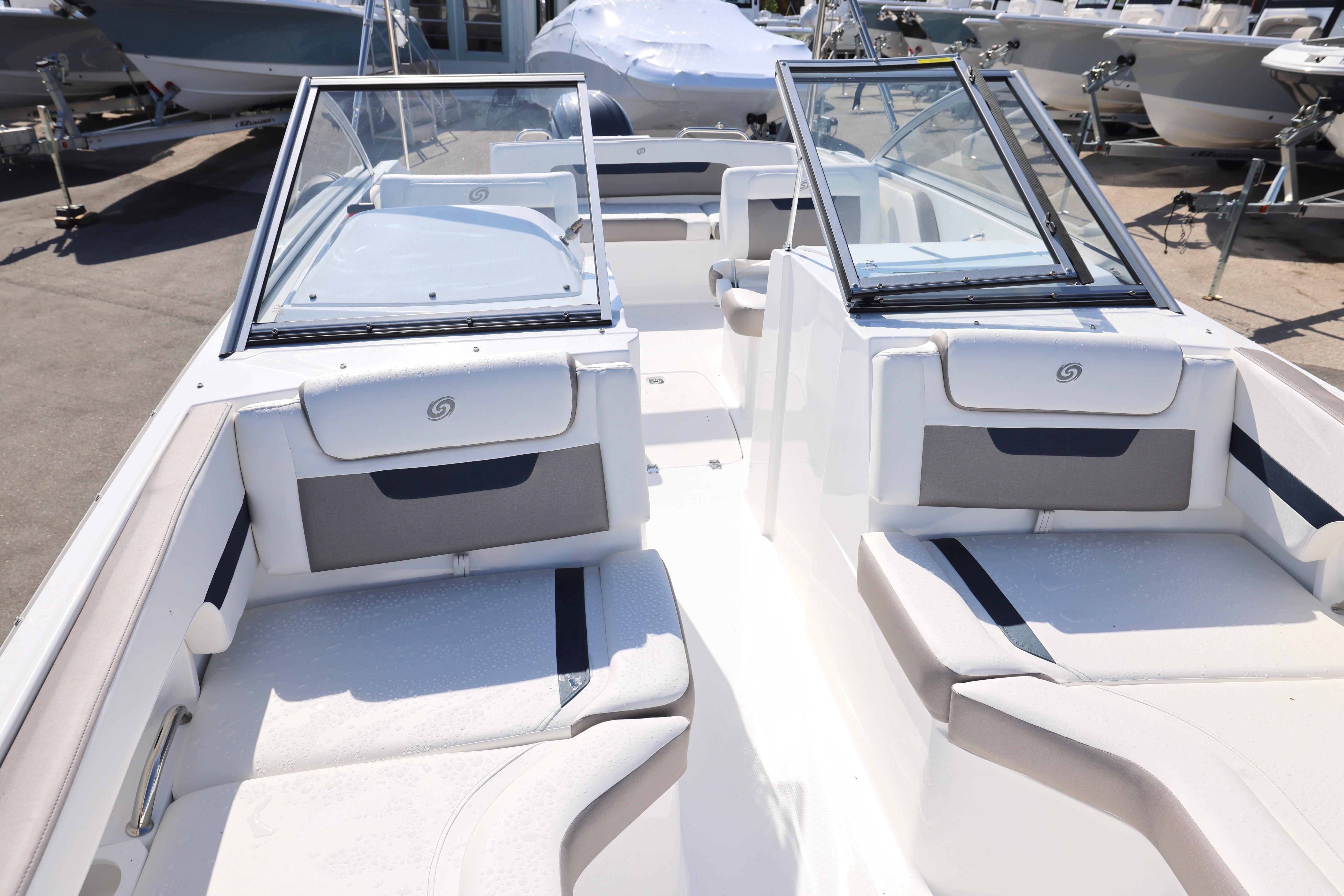 2026 Hurricane SunDeck 235 OB boat interior with seating and windshield, displayed outdoors.